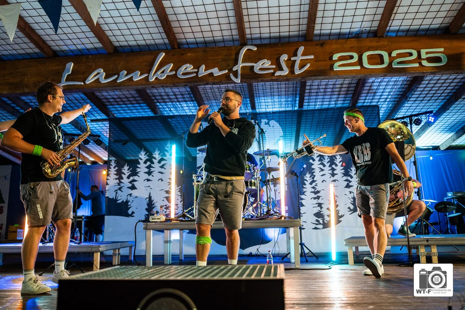Brass Buebe auf der Bühne während eines Festes, mit einem großen Banner im Hintergrund, das 'Lankenfest 2025' zeigt, bei nächtlicher Beleuchtung.