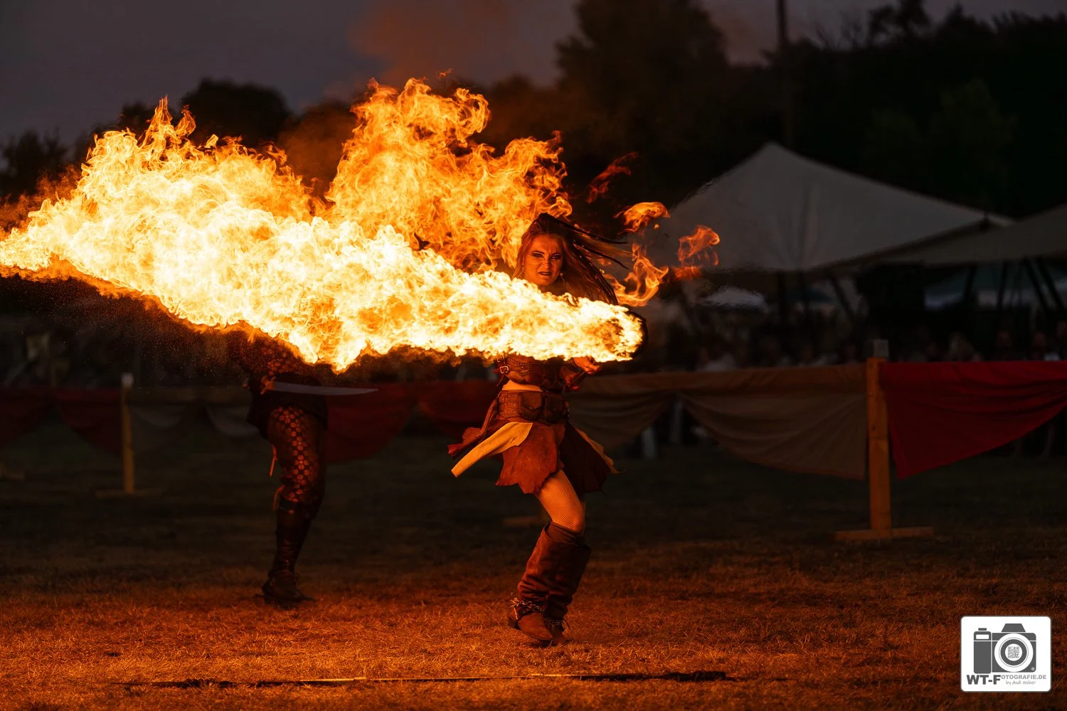 Feuer- oder Flammenjongleur bei einer Performance auf einem Festival, nachts, im Freien.