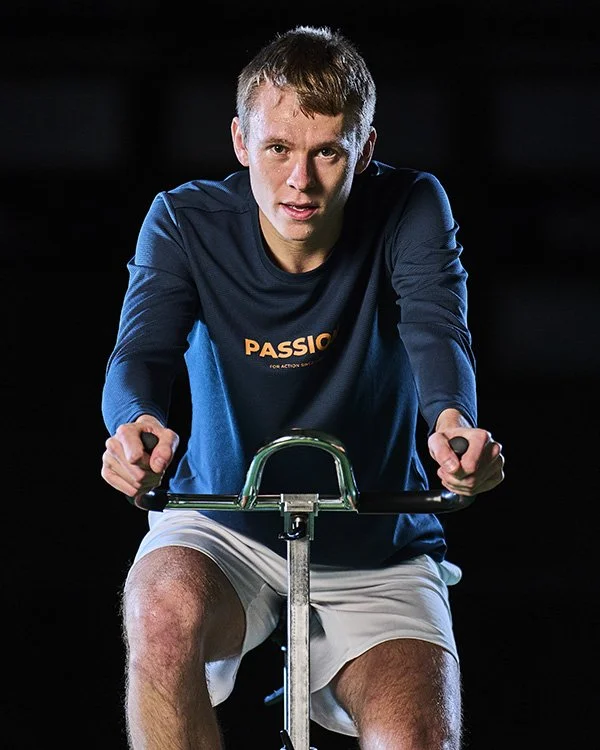 En ung mand, der cykler på en træningsstation i et mørkt rum.