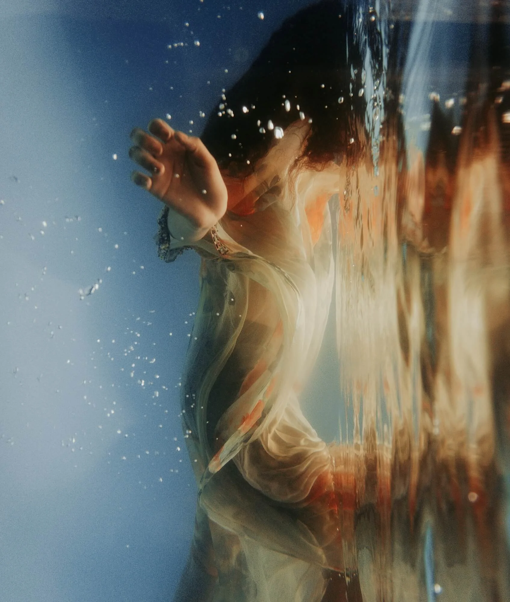 Woman reflected in water, representing emotional awareness and self-exploration in holistic therapy.