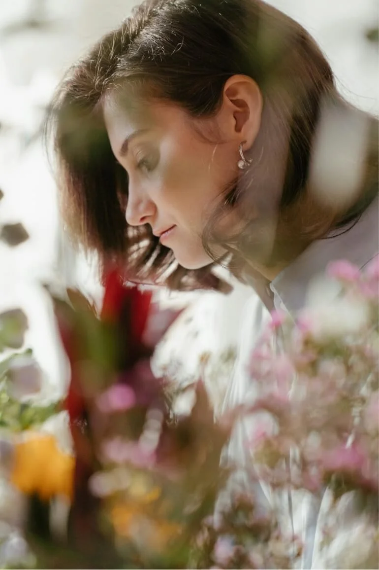 Woman surrounded by flowers in a reflective moment, representing self-awareness in trauma therapy.