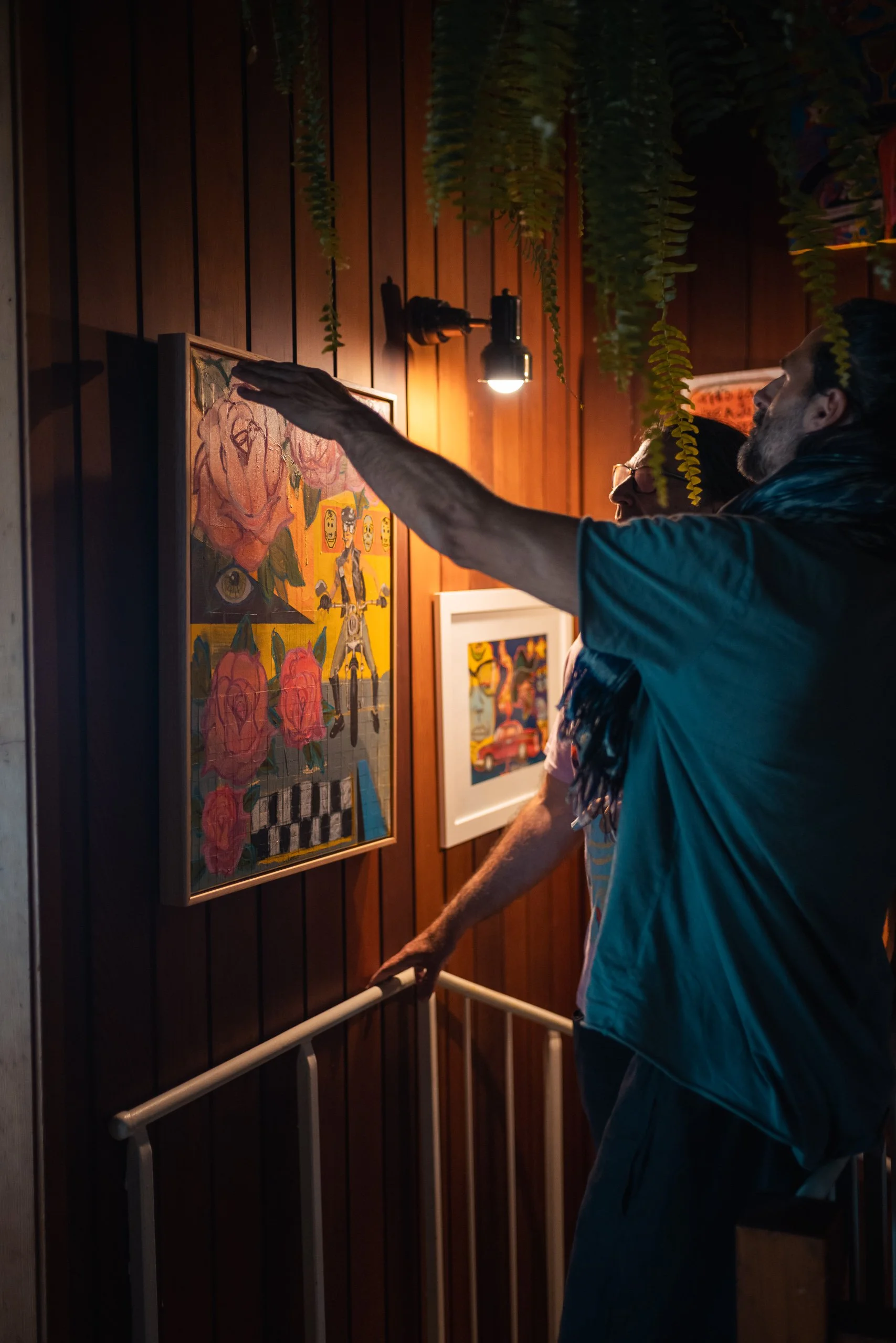 Two men are observing artwork on a wooden wall in an art gallery.