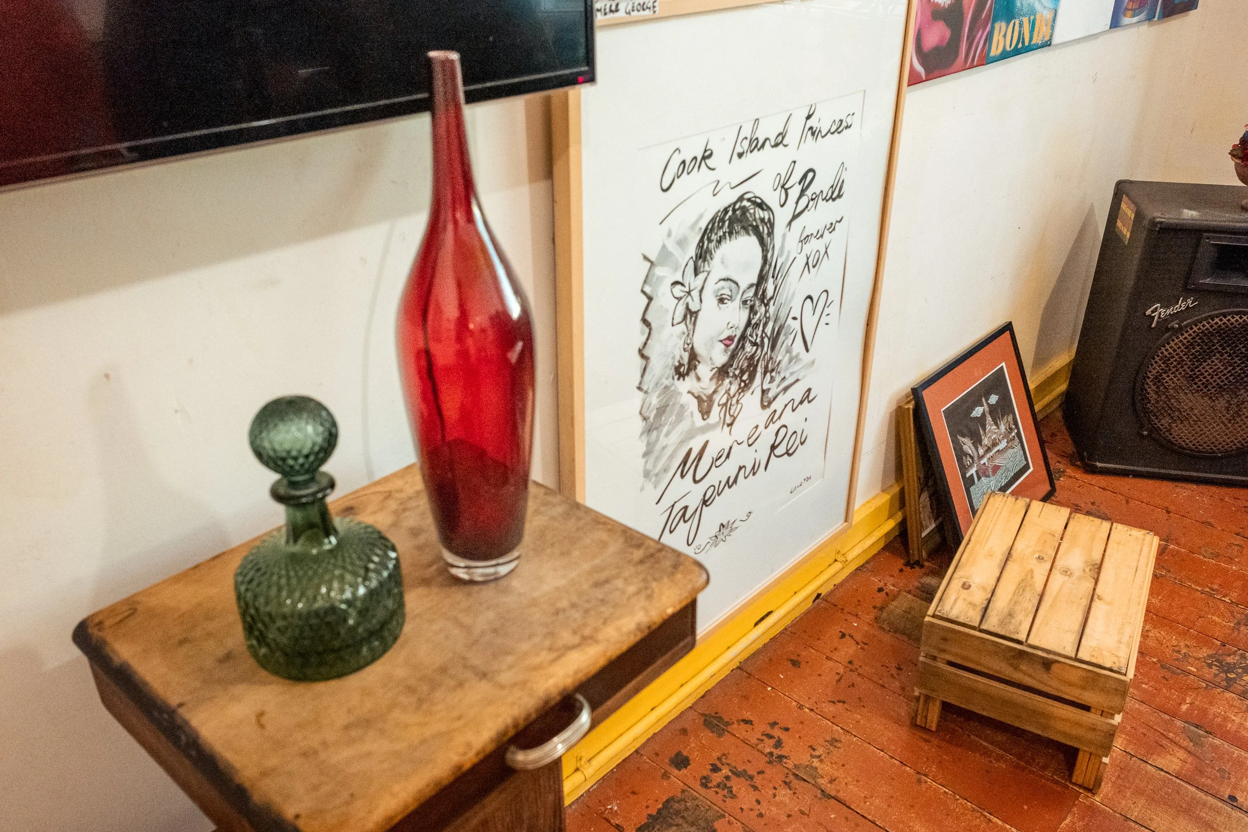 Decorative vases and framed artwork on wooden surfaces in a cozy room with yellow trim and a wooden floor.
