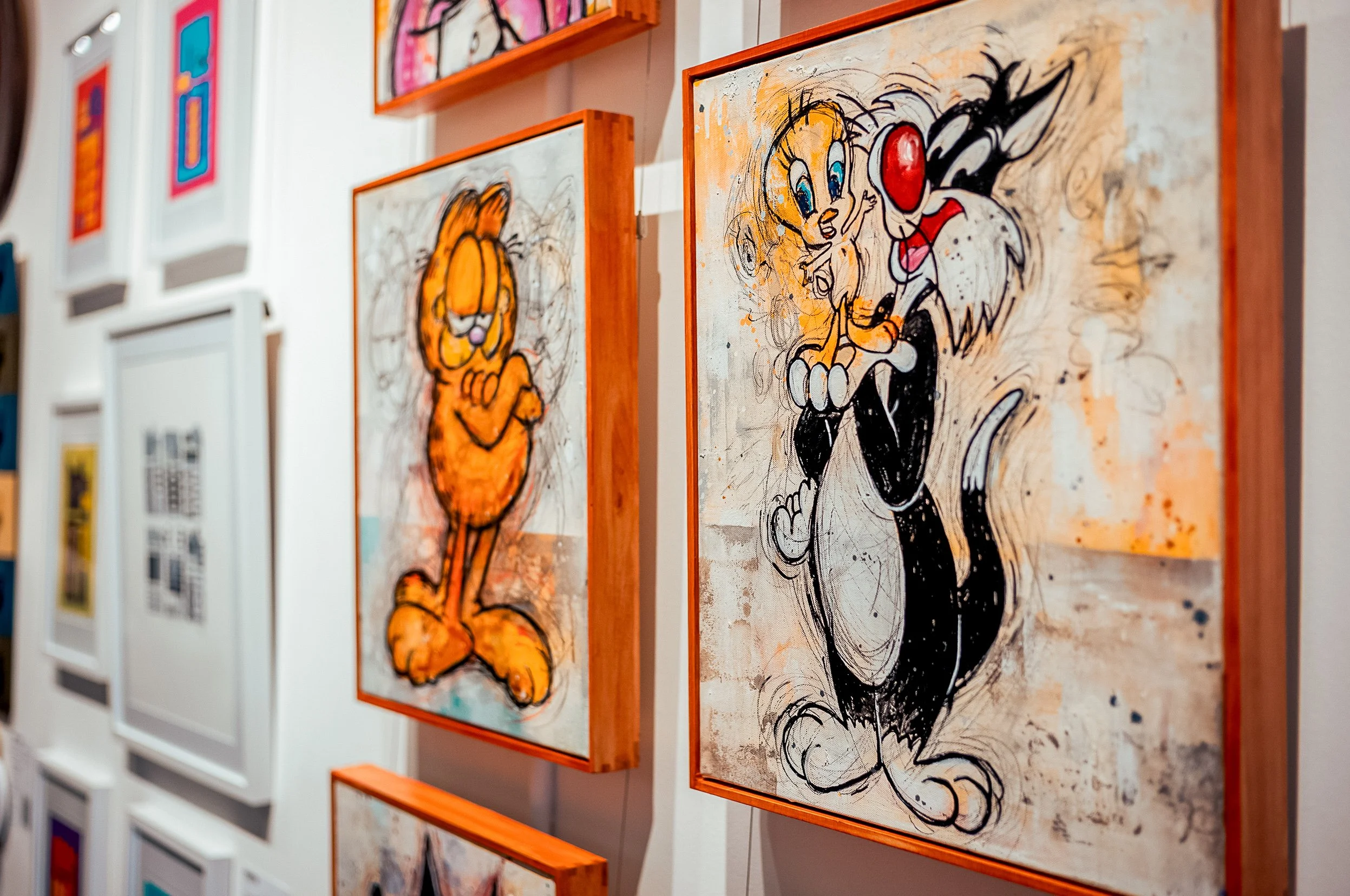 Gallery wall featuring abstract and expressive artwork of cartoon characters, including Garfield and other characters, in a modern art style.
