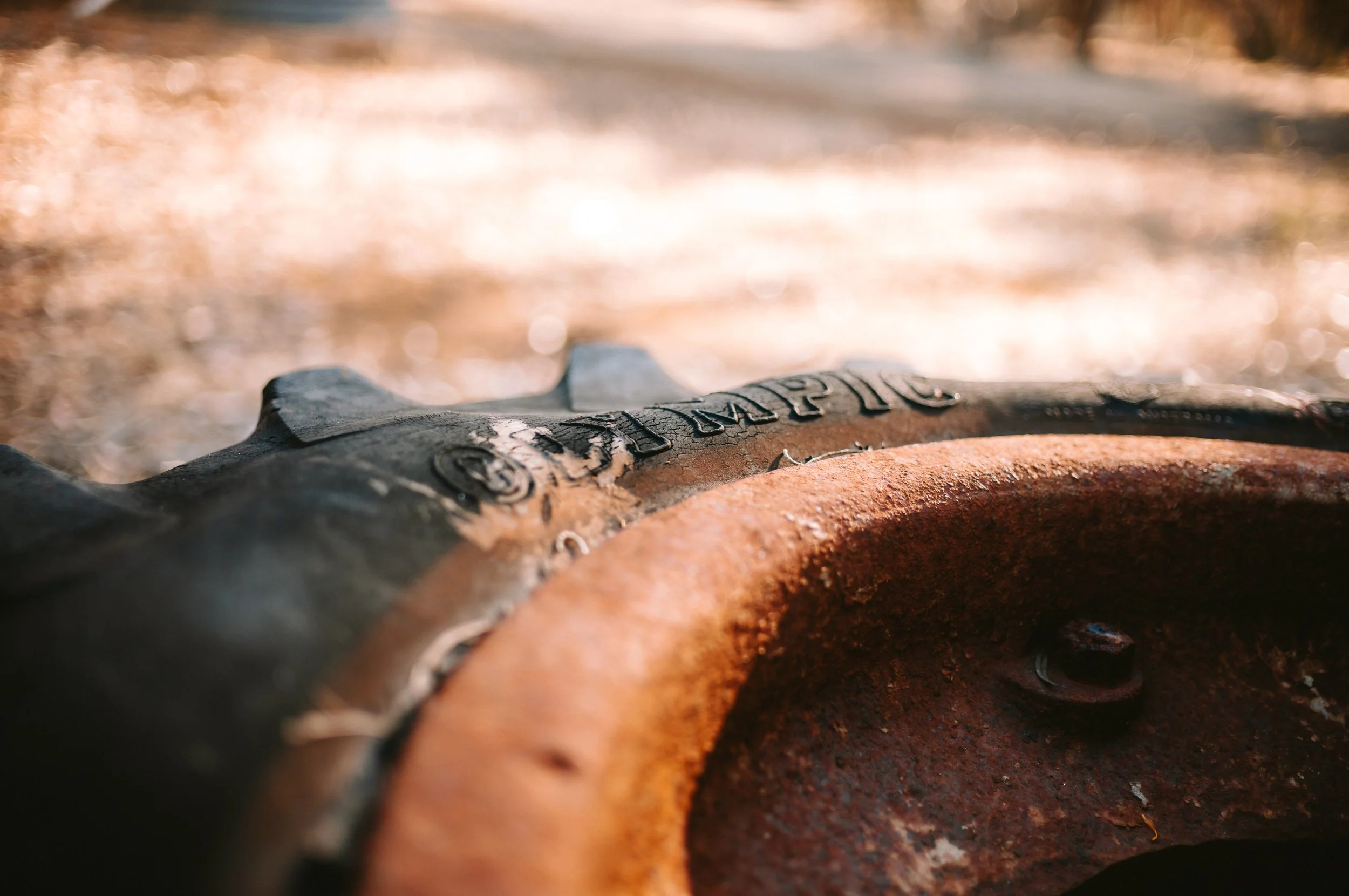 Close-up of a rusty, weathered, black and orange Stanley brand shovel resting on a dirt surface, with a blurred background.