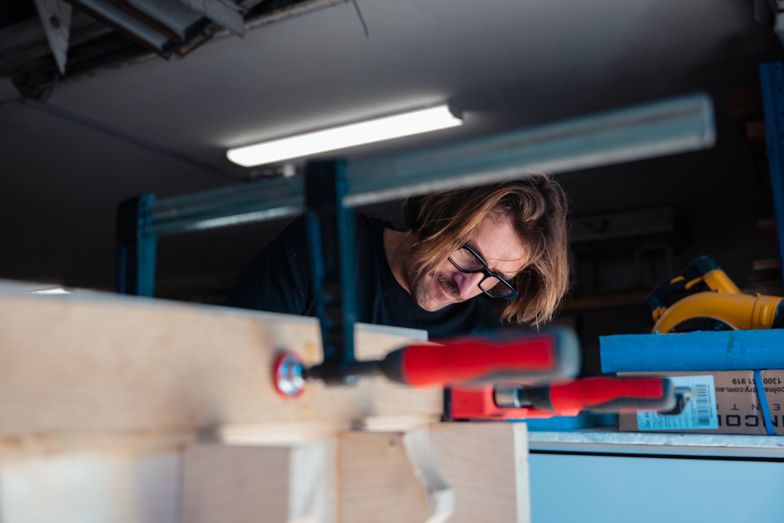 Man working on woodworking project with clamps in a workshop.