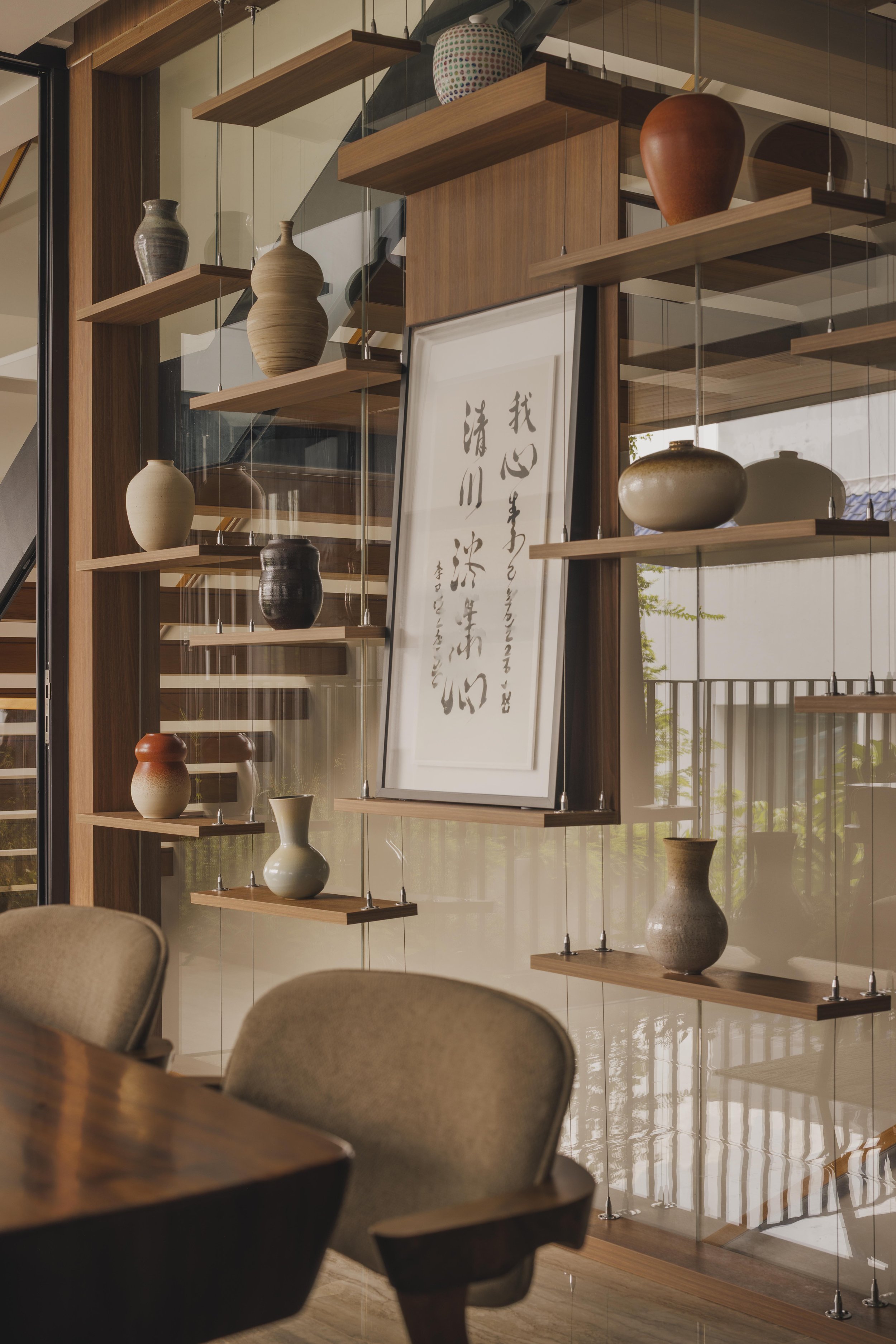 Wooden shelves with various pottery vases in a modern interior with a framed calligraphy artwork.