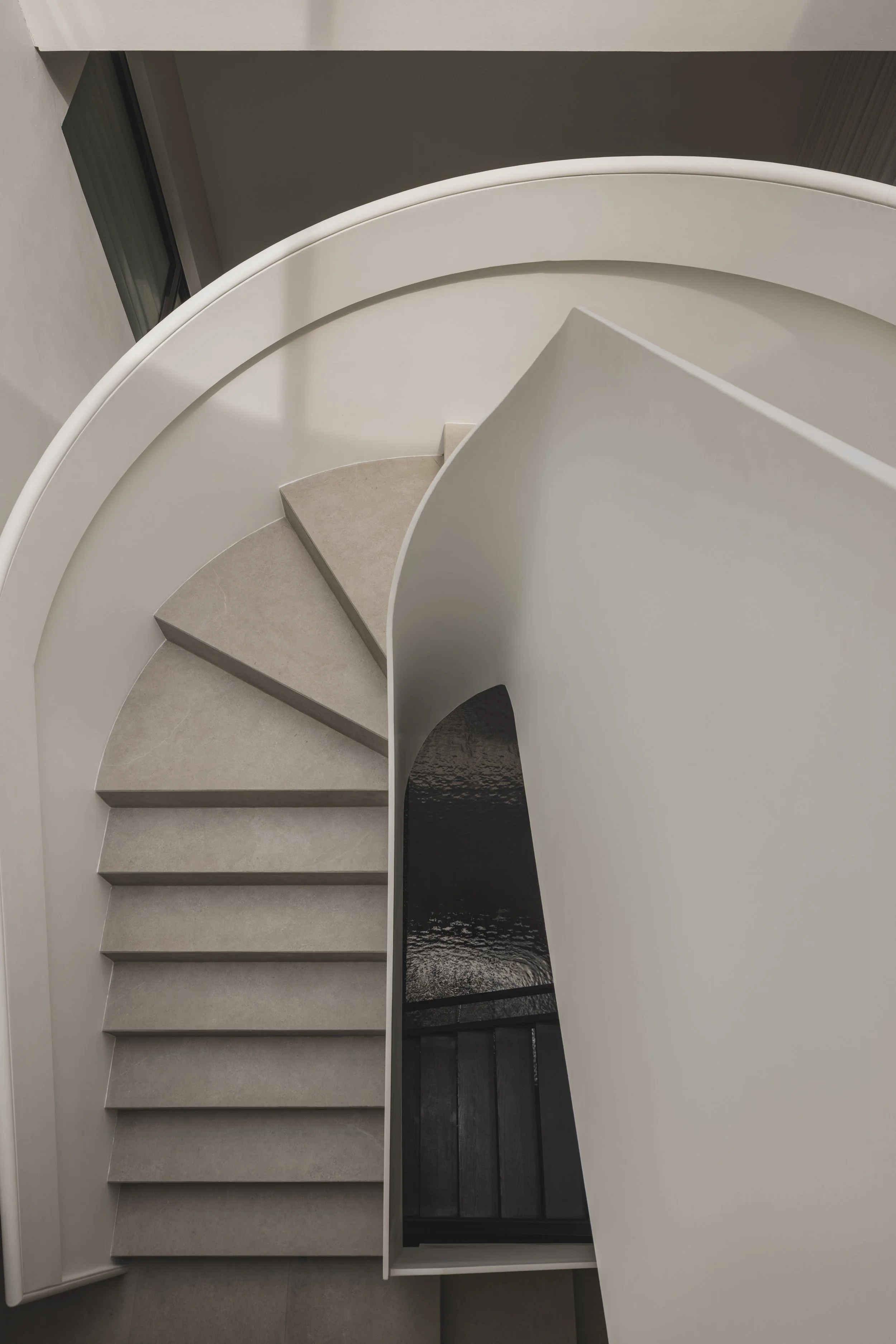 Side-by-side comparison of two staircases, one with a white curved railing and beige steps, and the other with a black railing and dark wooden steps, with a reflective water surface visible through a window.