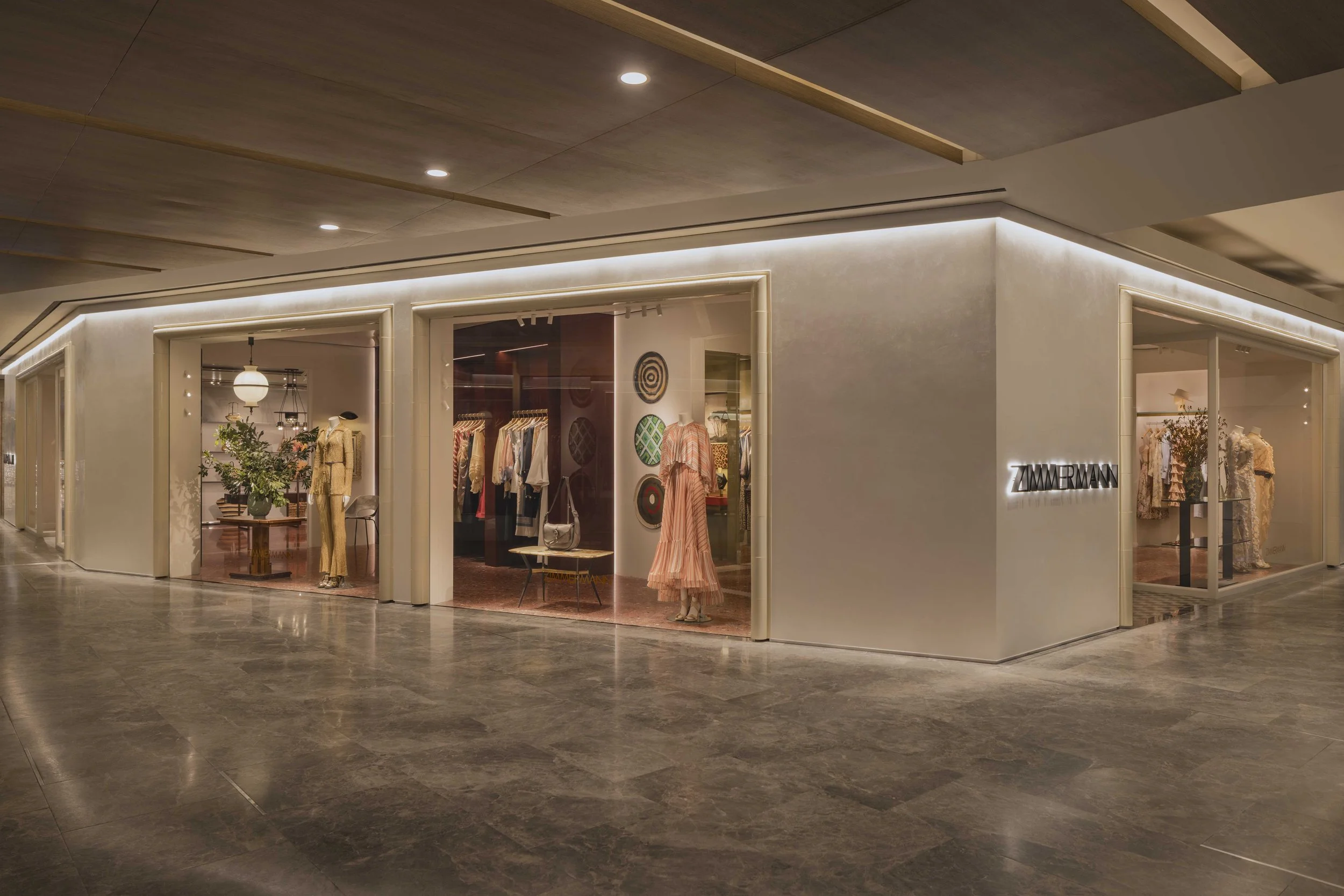 Fashion boutique with clothing displays, mannequins, and decorative wall art, inside a shopping mall.