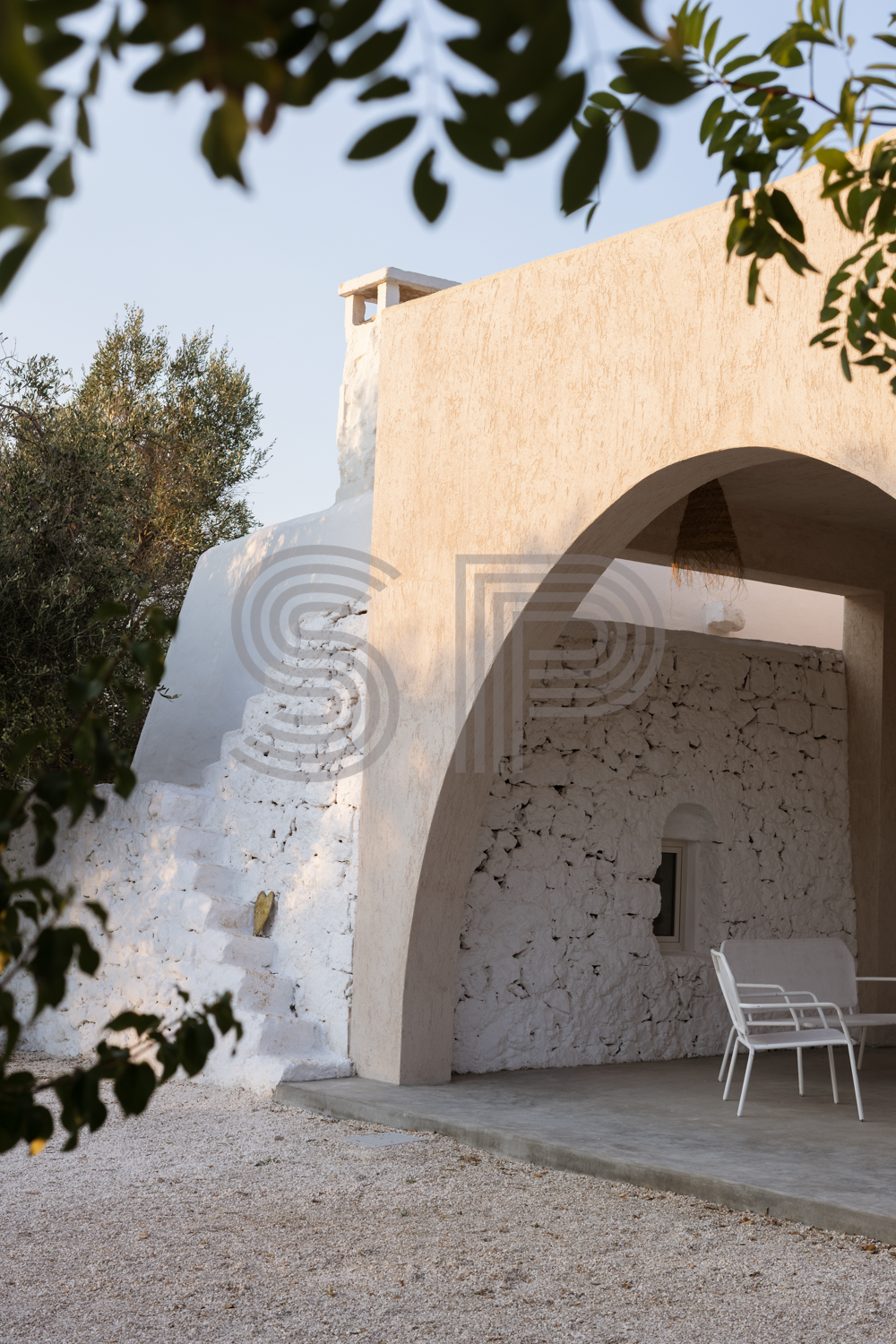 Ancient stone trullo incorporated into a contemporary villa with large arched portico.
