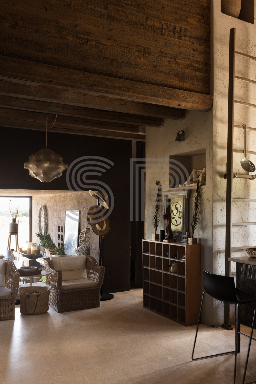 Contemporary Puglia house interior with double-height ceiling, exposed concrete finishes, dark textured walls and warm natural light