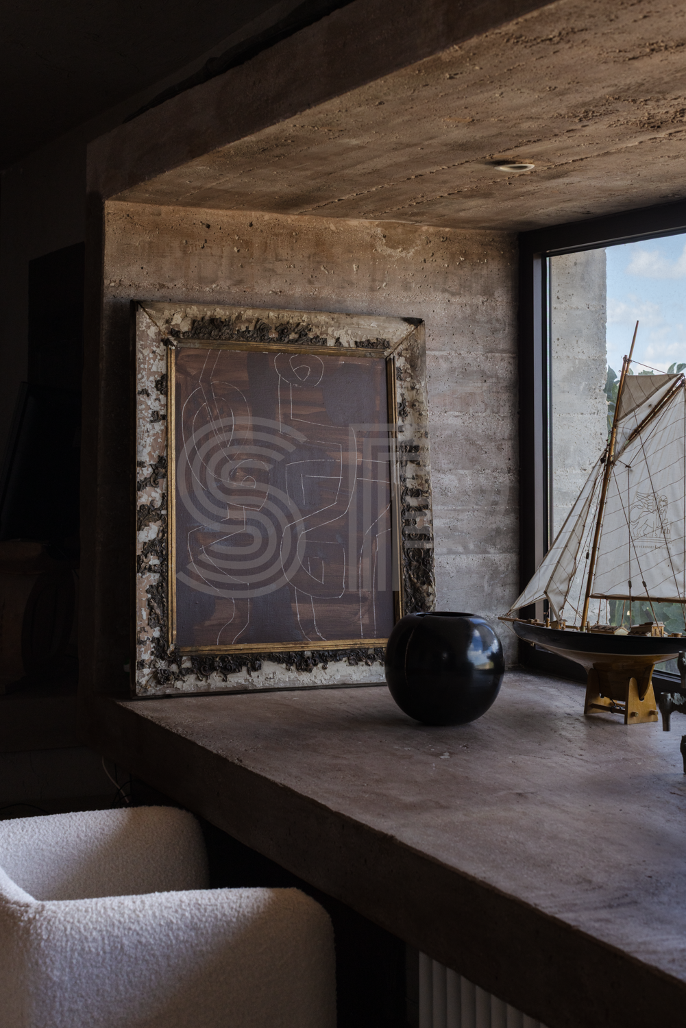 Brutalist-inspired shoot location in Puglia with raw concrete walls and ceiling, dark textured finishes and large window overlooking the garden