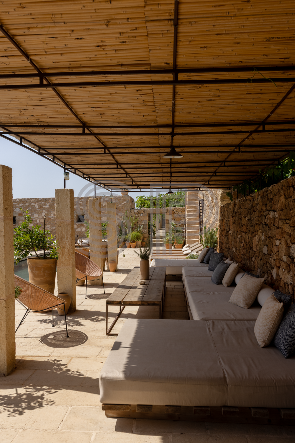 Covered outdoor living area with stone walls and built-in seating.