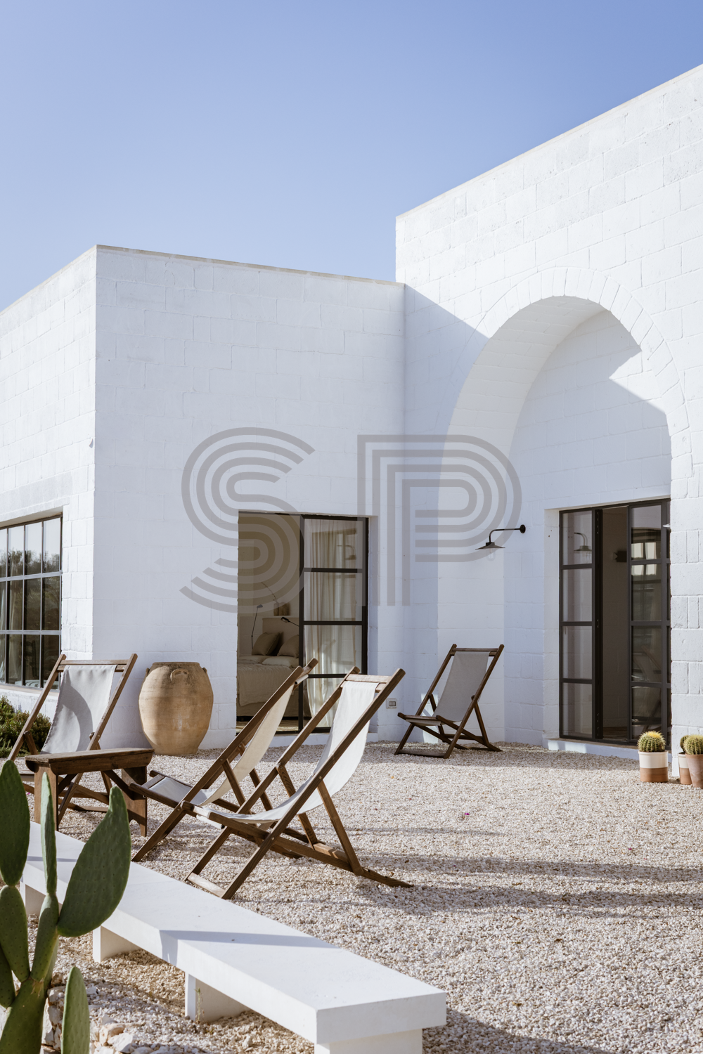 Contemporary white villa courtyard with dramatic arched architecture and gravel terrace.