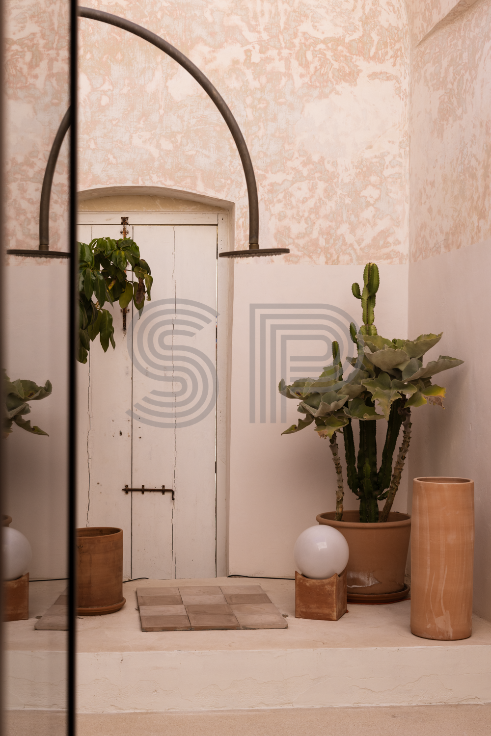 Riad-style shower room courtyard in a Puglia Palazzo with distressed pink lime plaster walls, arched architecture and Mediterranean planting