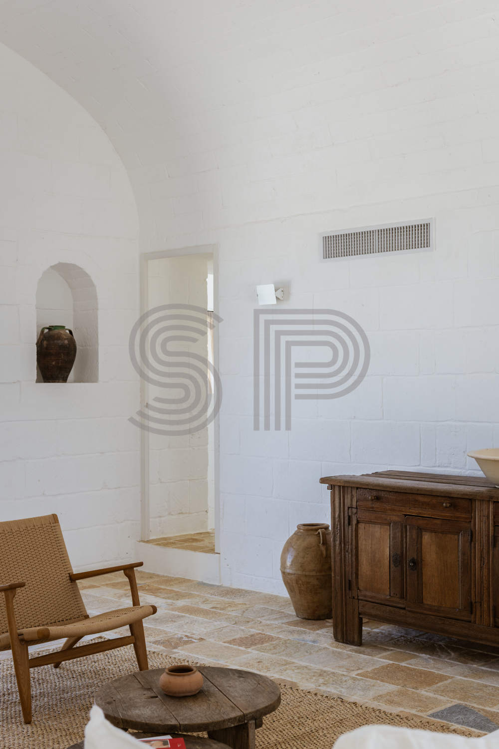 Contemporary Puglia villa interior with white vaulted architecture, natural stone flooring and warm neutral tones