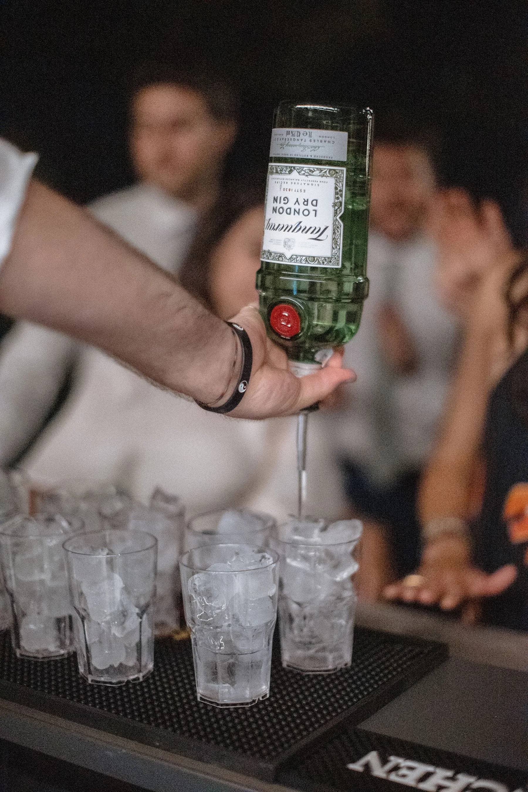 Una mano versa un cocktail da una bottiglia di gin londinese in bicchieri con ghiaccio su un bancone.
