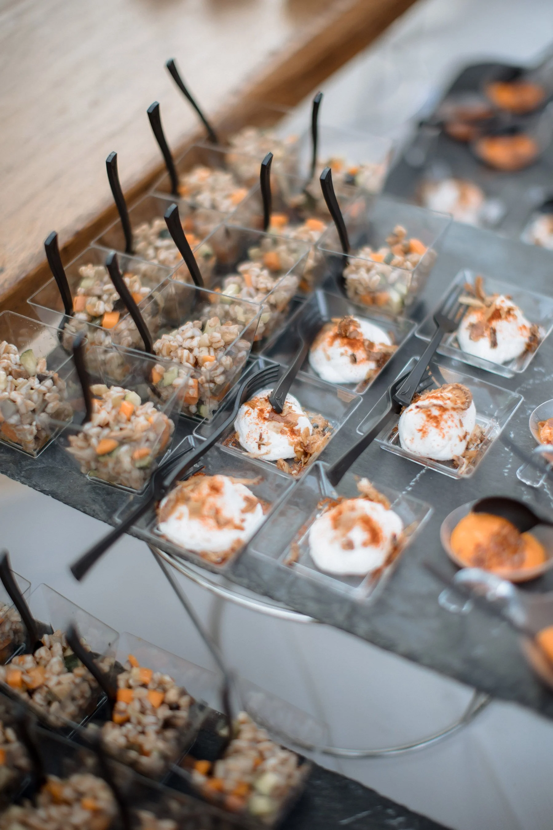 Assortimento di dessert in bicchieri quadrati, alcuni con panna, altri con mix di frutta e cioccolato, decorati con spezie