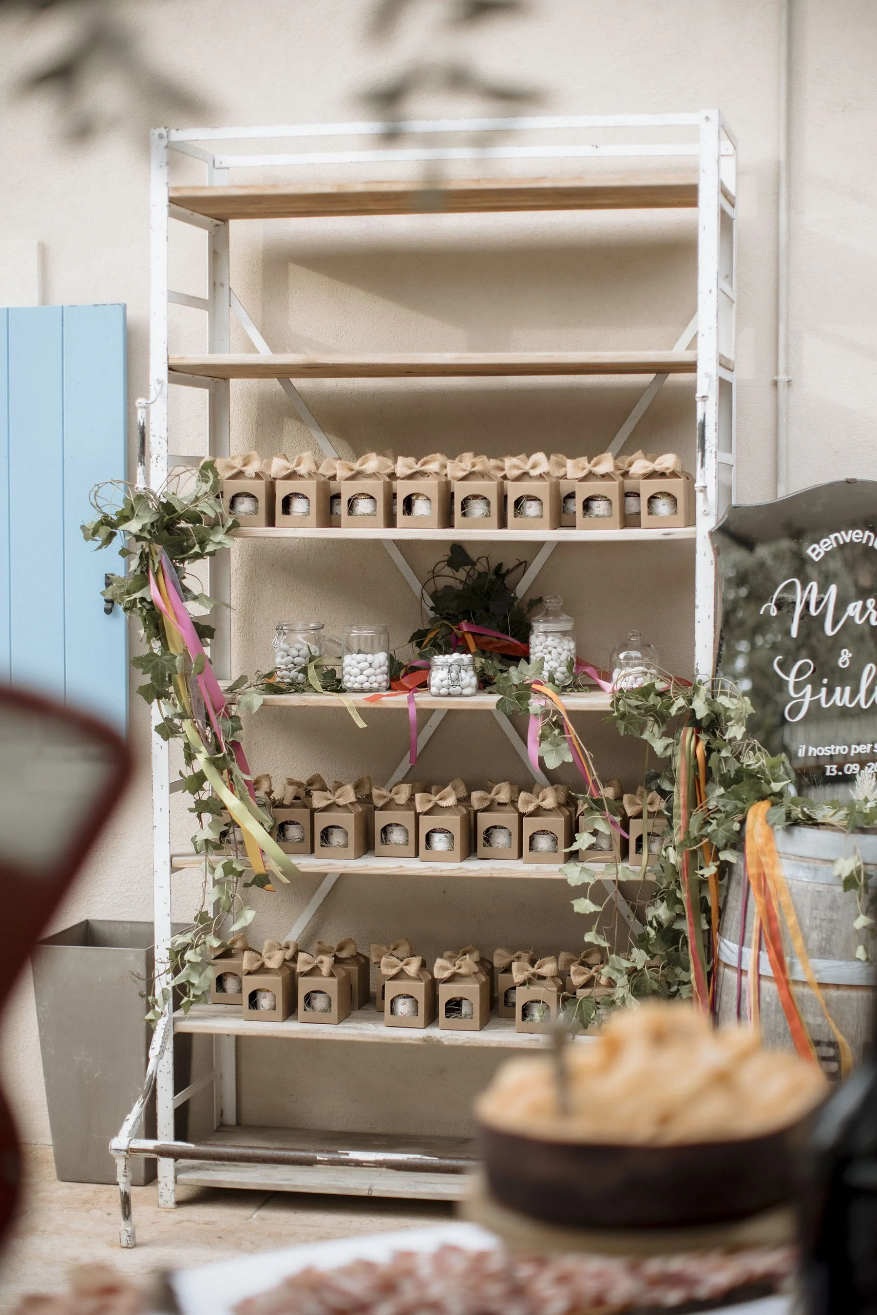 Scaffale decorato con barattoli e confezioni, decorato con foglie e nastri colorati, vicino a un cartellone di benvenuto.