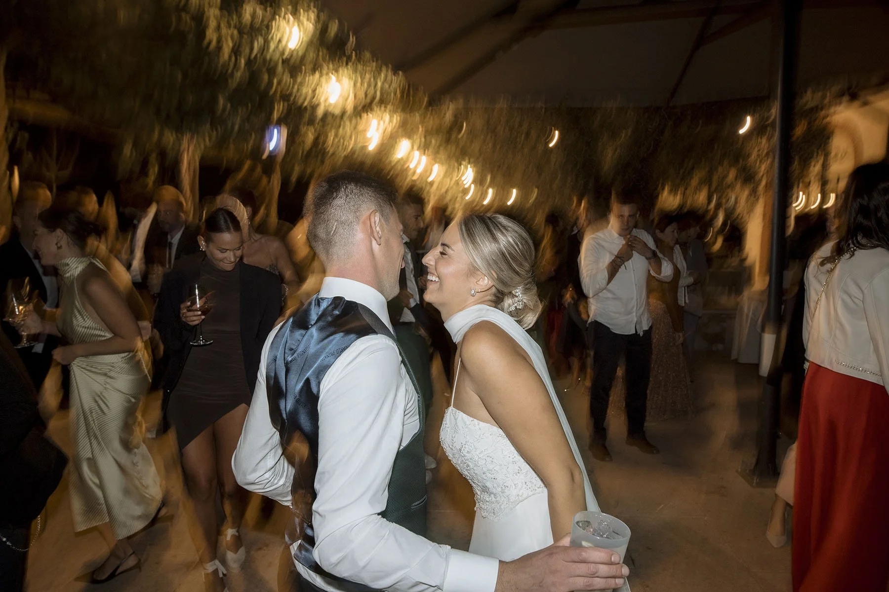 Coppia di sposi ballano felici a un matrimonio con amici e parenti.