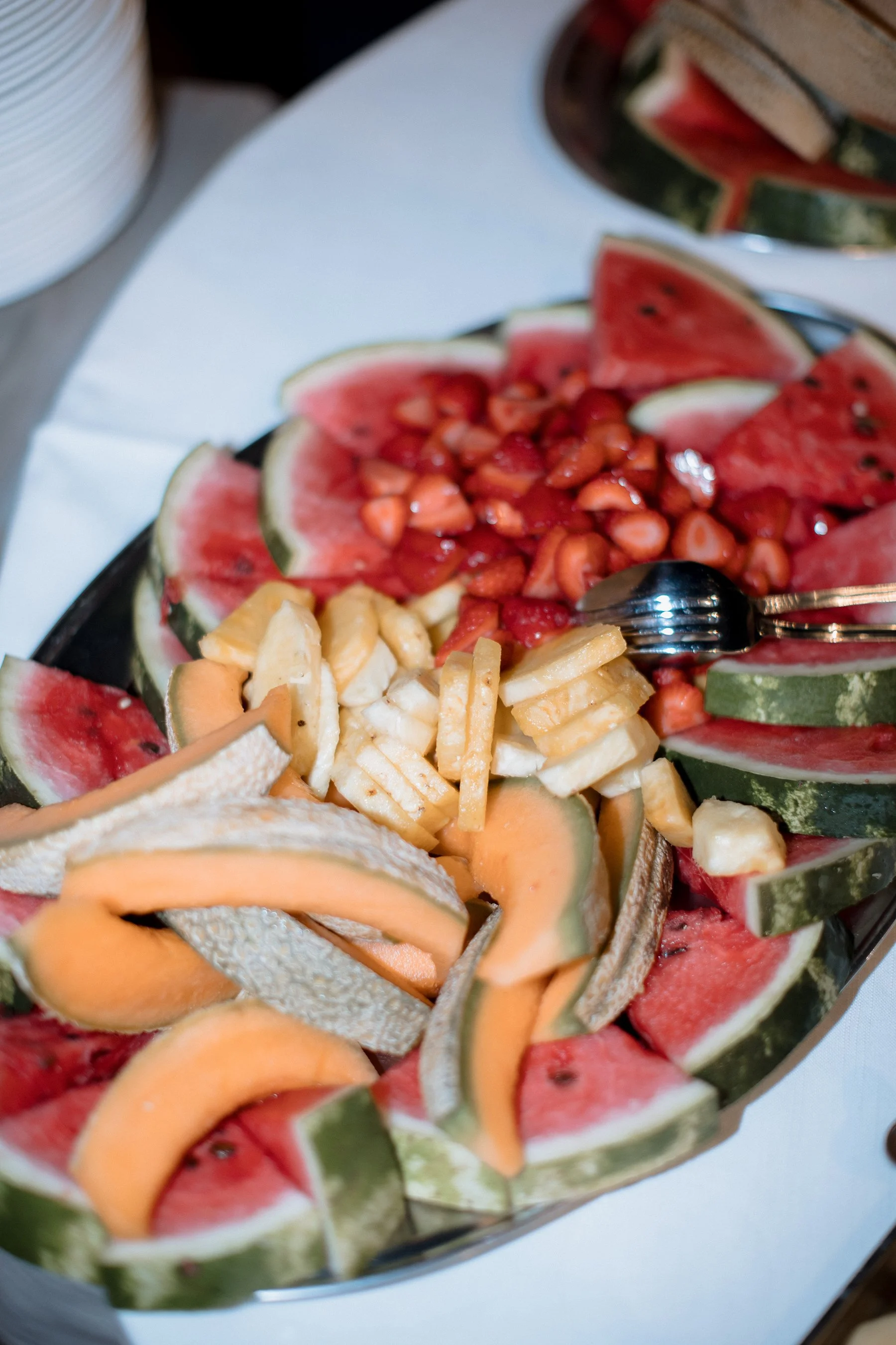 Piattino di frutta con fette di anguria, melone, fragole e pesche, decorato in modo colorato.