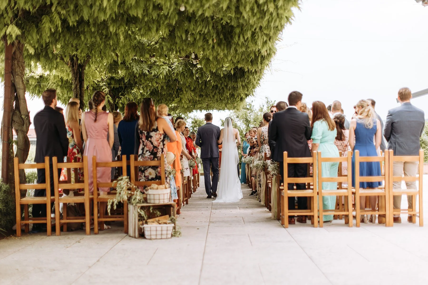 Coppia di sposi che cammina lungo il corridoio durante un matrimonio all'aperto, circondati da amici e parenti