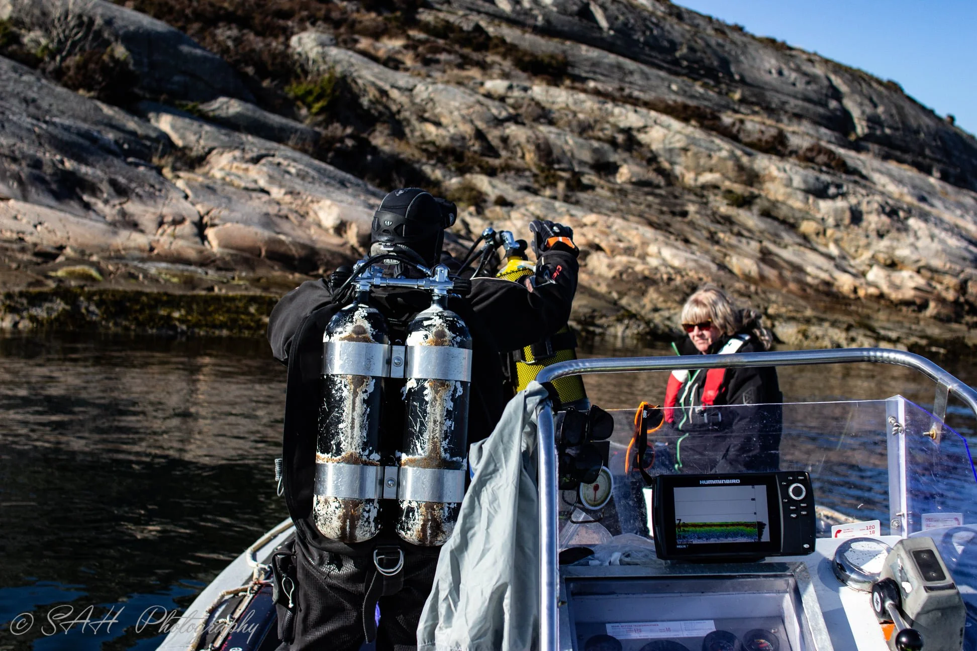 en dykker ombord i en båt foran en øy.