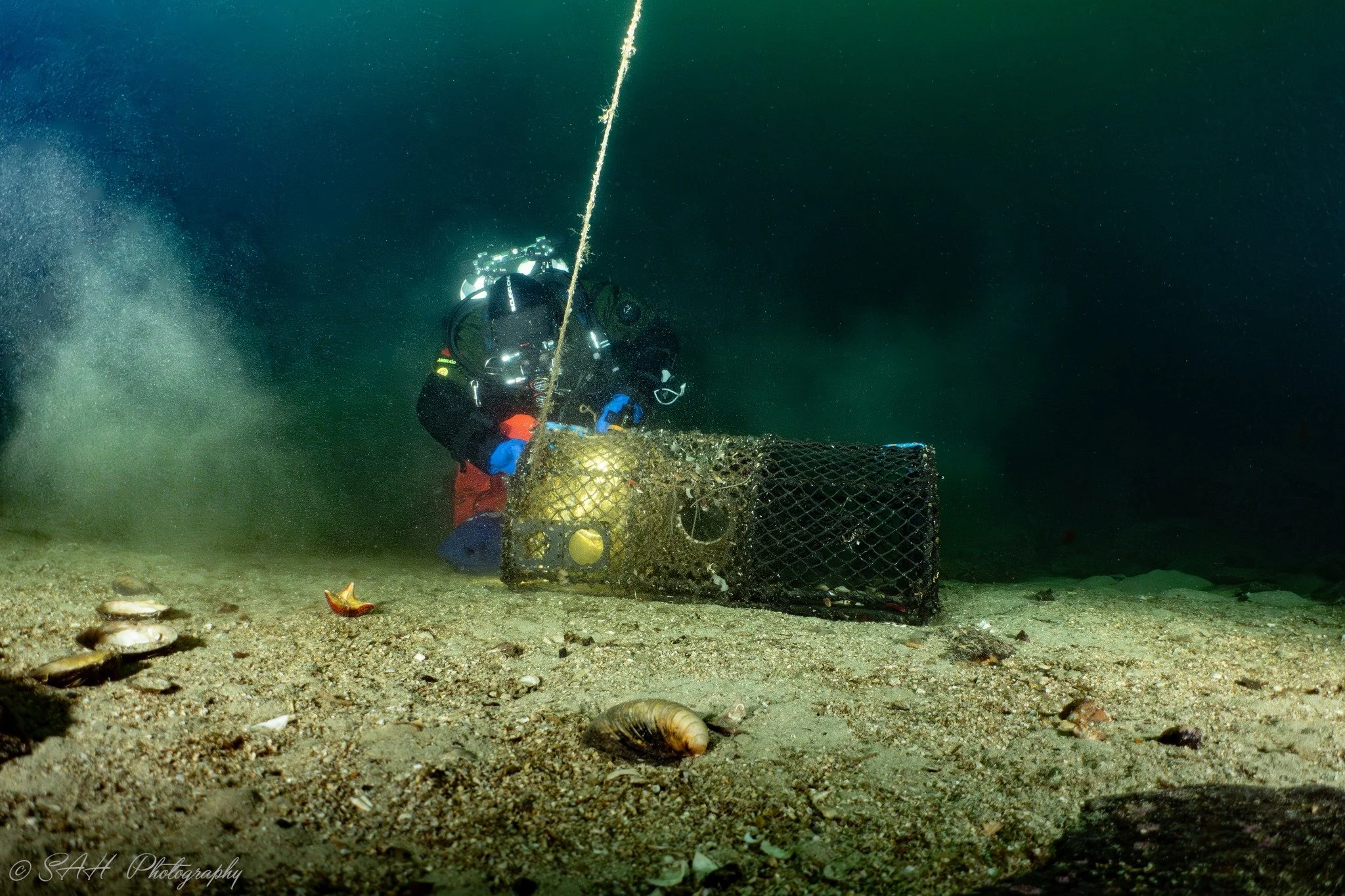 dykker fester et flyteelement for å heve en spøkelsesteine.