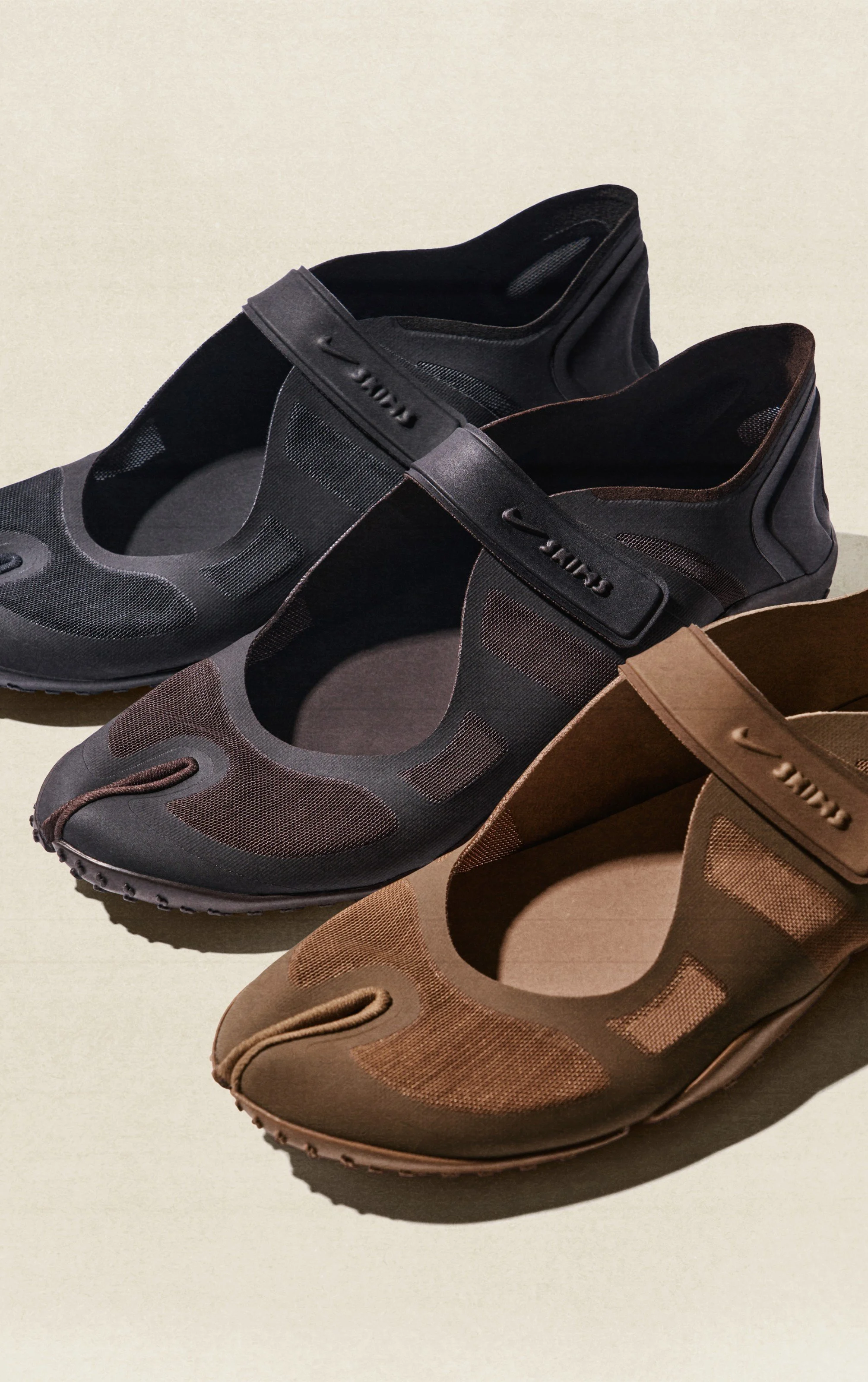 Drei Wanderschuhe in Schwarz, Grau und Braun auf einer hellen Oberfläche