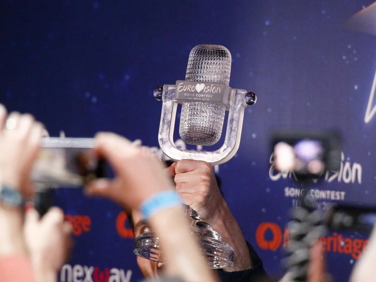 Frau in einem weißen Kleid und einer weißen Kopfbinde steht gegen den blauen Himmel, die Augen geschlossen.