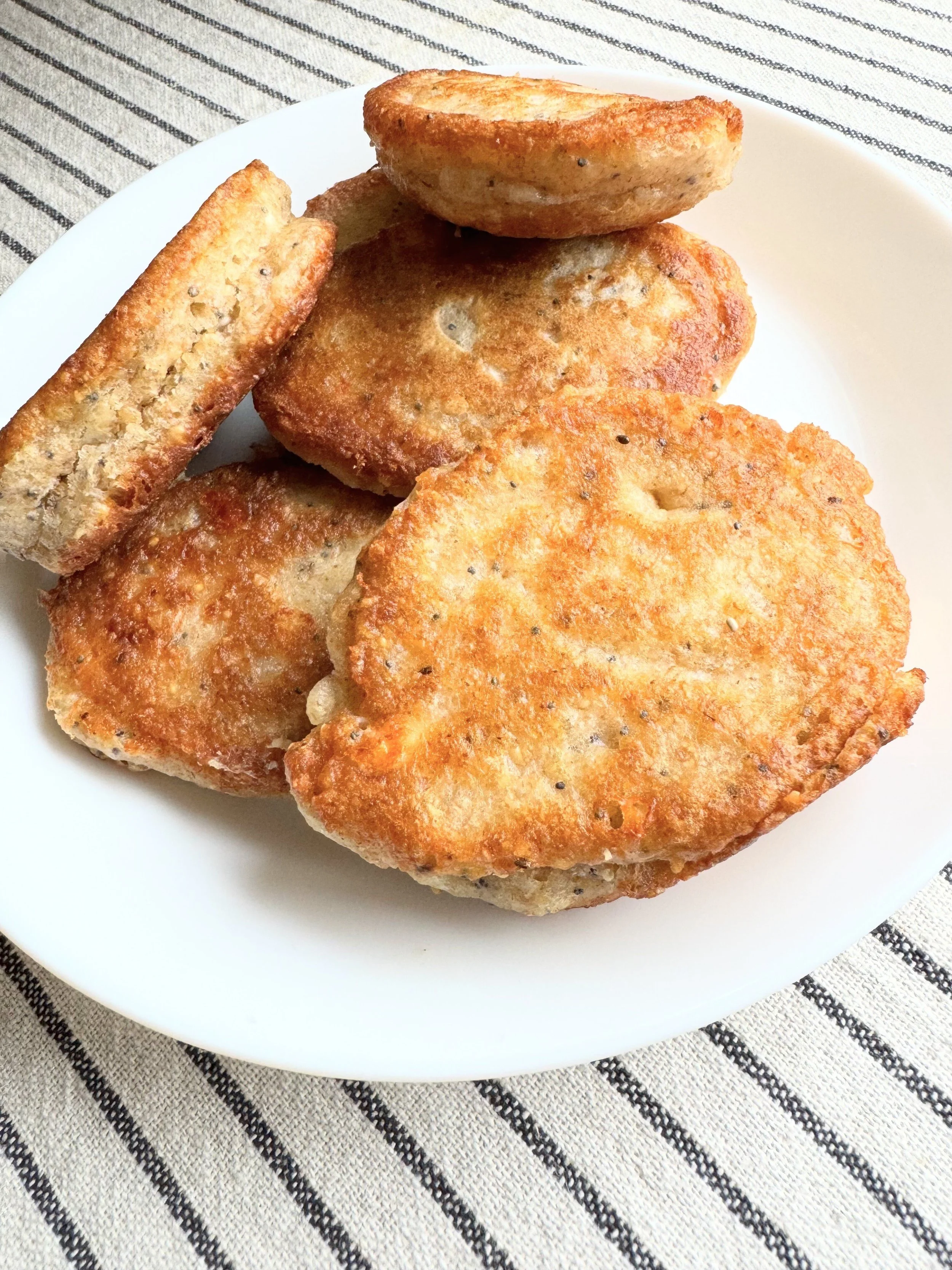 A plate of fried pancakes on a striped tablecloth