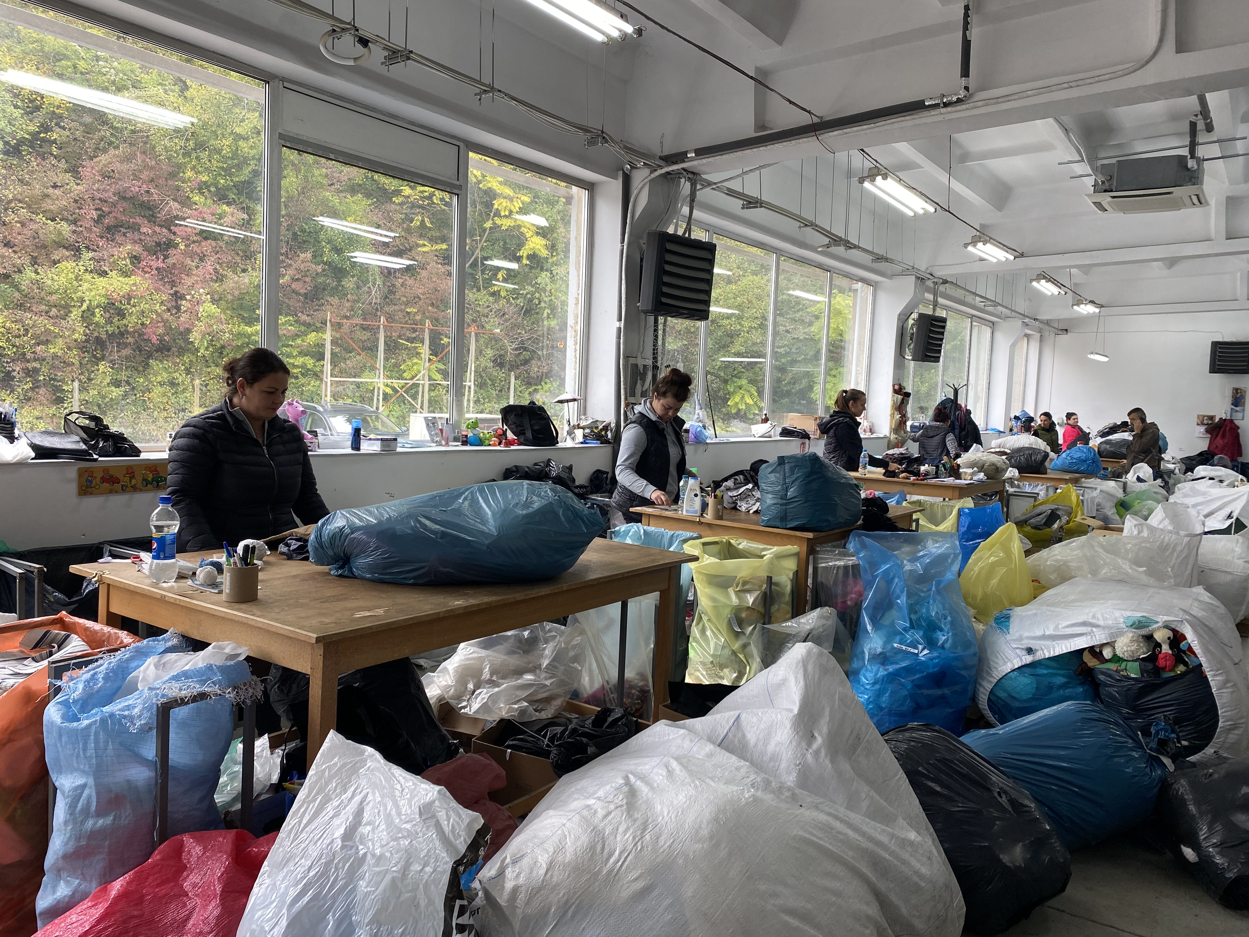 Volontärer och arbetare i Kosovo sorterar donationer som har kommit från en second hand i Lidköping för att de ska kunna sälja det i sina egna second hand-butiker.