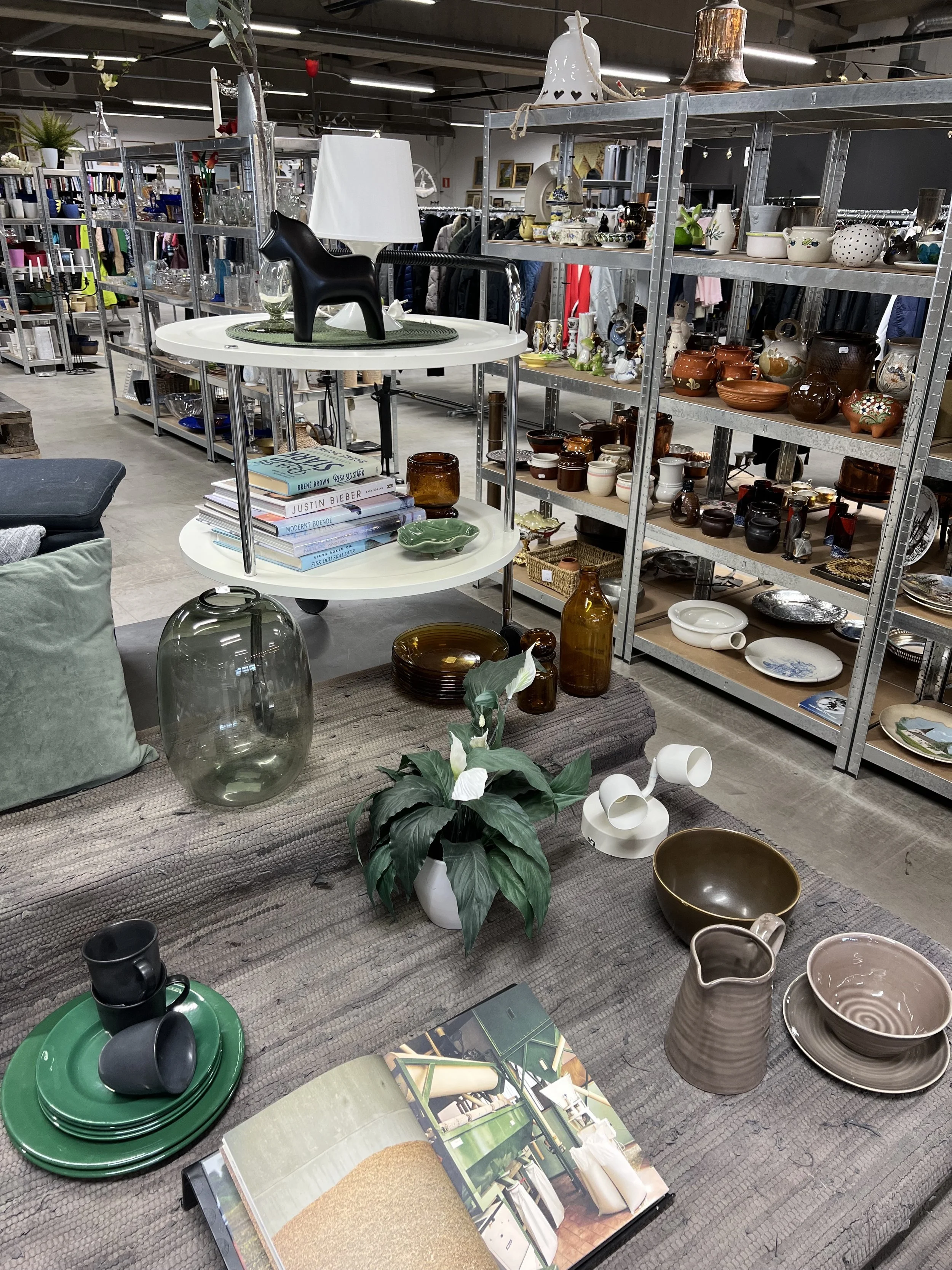 Inrednings- och prydnadssaker på ett second hand-varuhus med hyllor och bord.