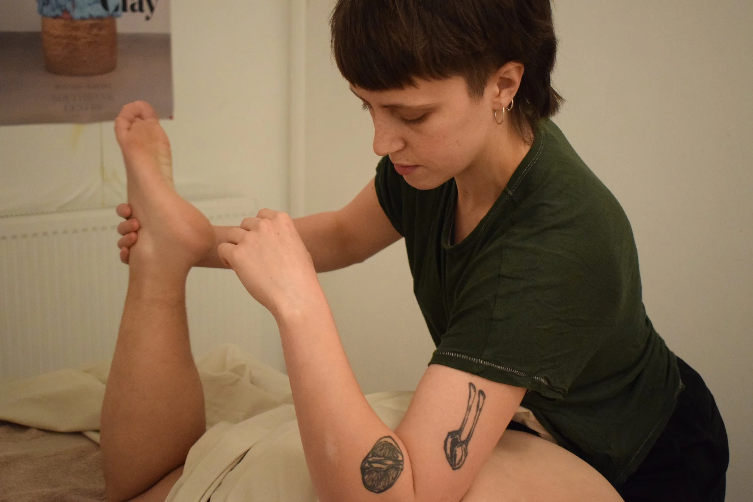A person with tattoos on their arm is giving a massage to a client.
