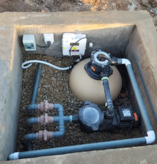 Sistema de filtración y bombeo de agua para piscina con tuberías, filtro, bombas y componentes eléctricos instalados en un recámara de concreto.