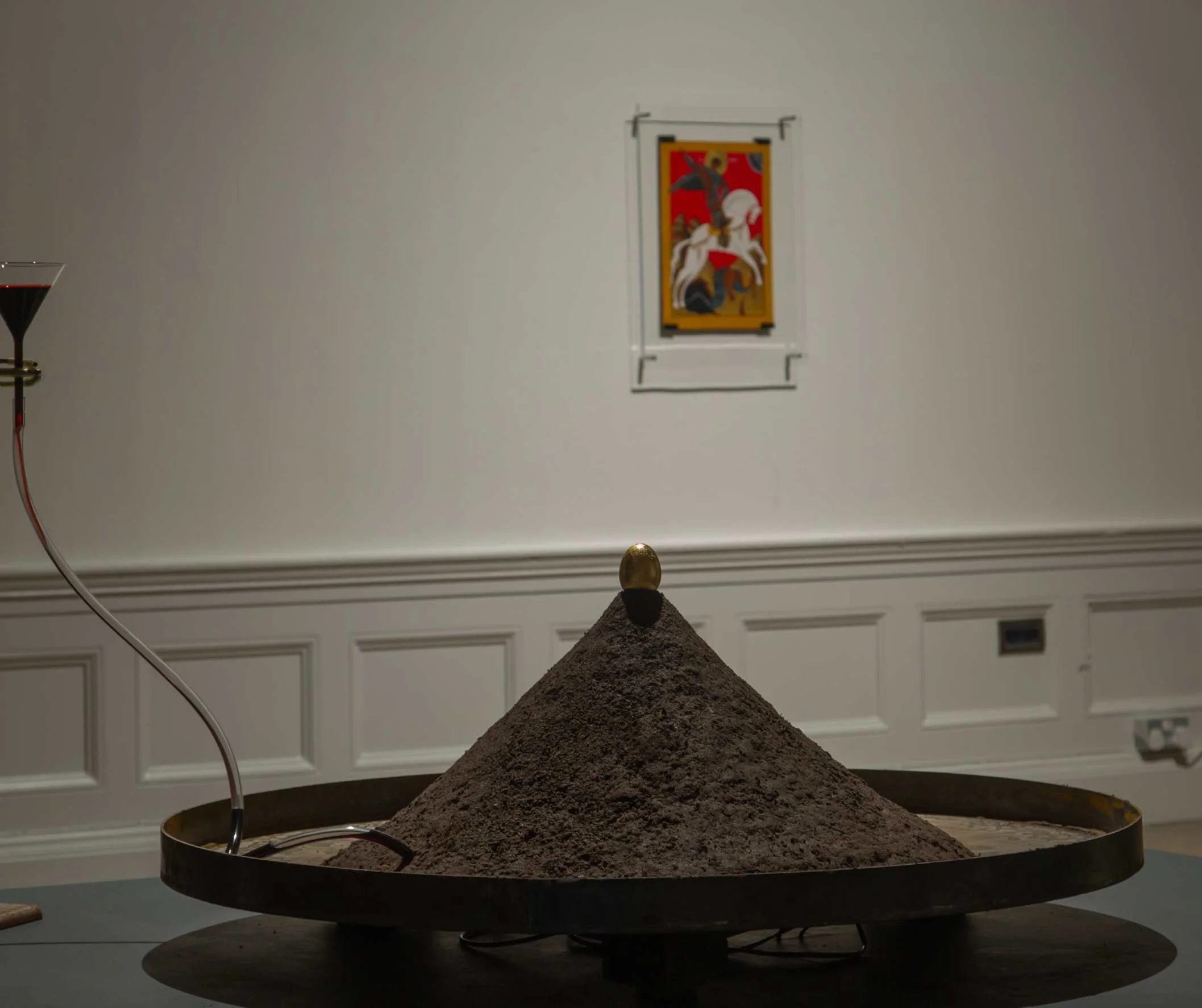 ANGELO MADONNA THE ALCHEMY OF BLOOD AND RENEWAL (2024) 

Mild steel plate - Soil/clay - Glass funnel - red ink - golden egg 

In a tale reminiscent of Sir Gawain and the Green Knight, the blood-soaked earth undergoes a mystical alchemical process, tr