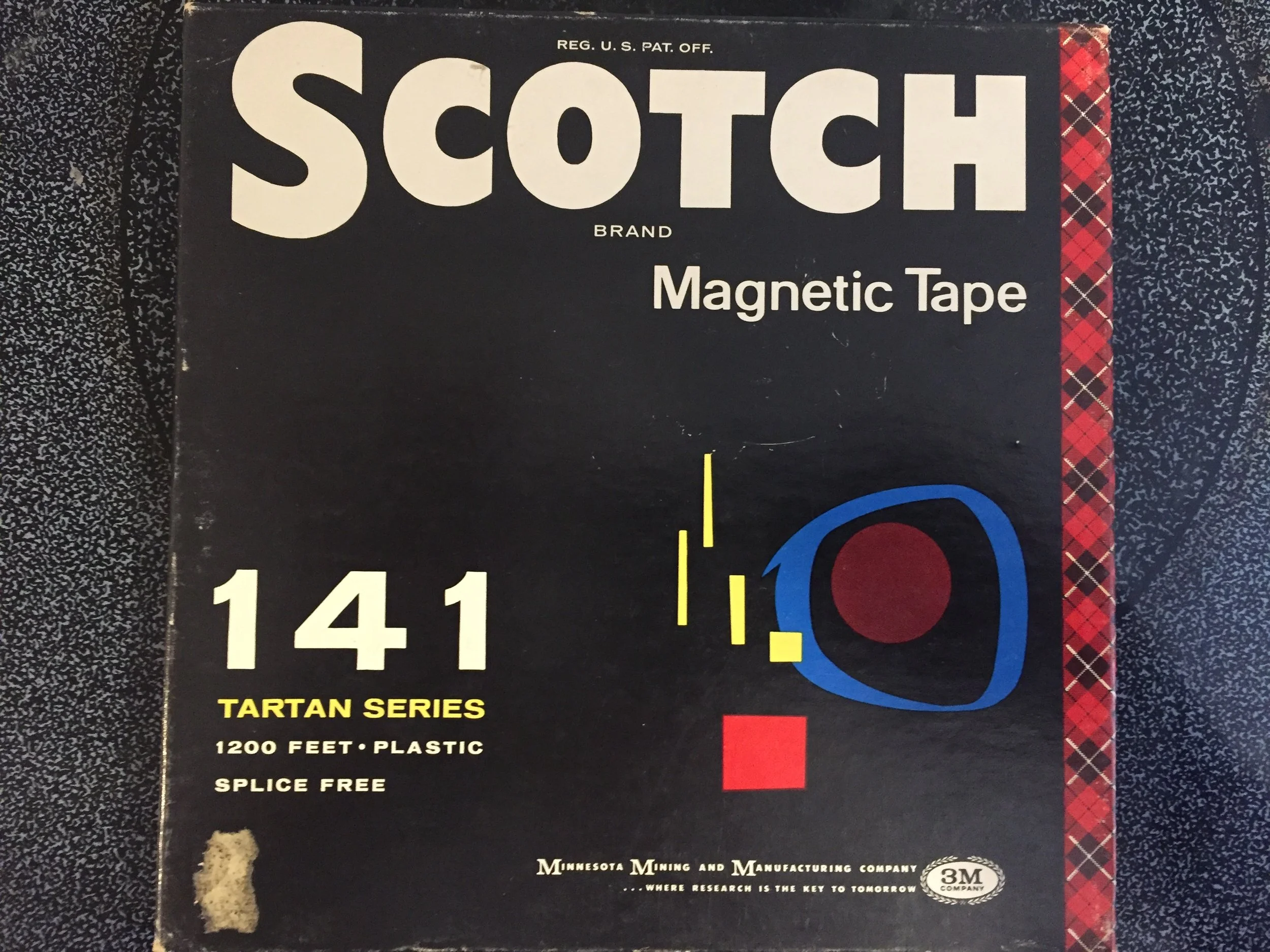 Close-up of a vintage box of Scotch brand magnetic tape, part of the Tartan Series, with details about length, material, and features.