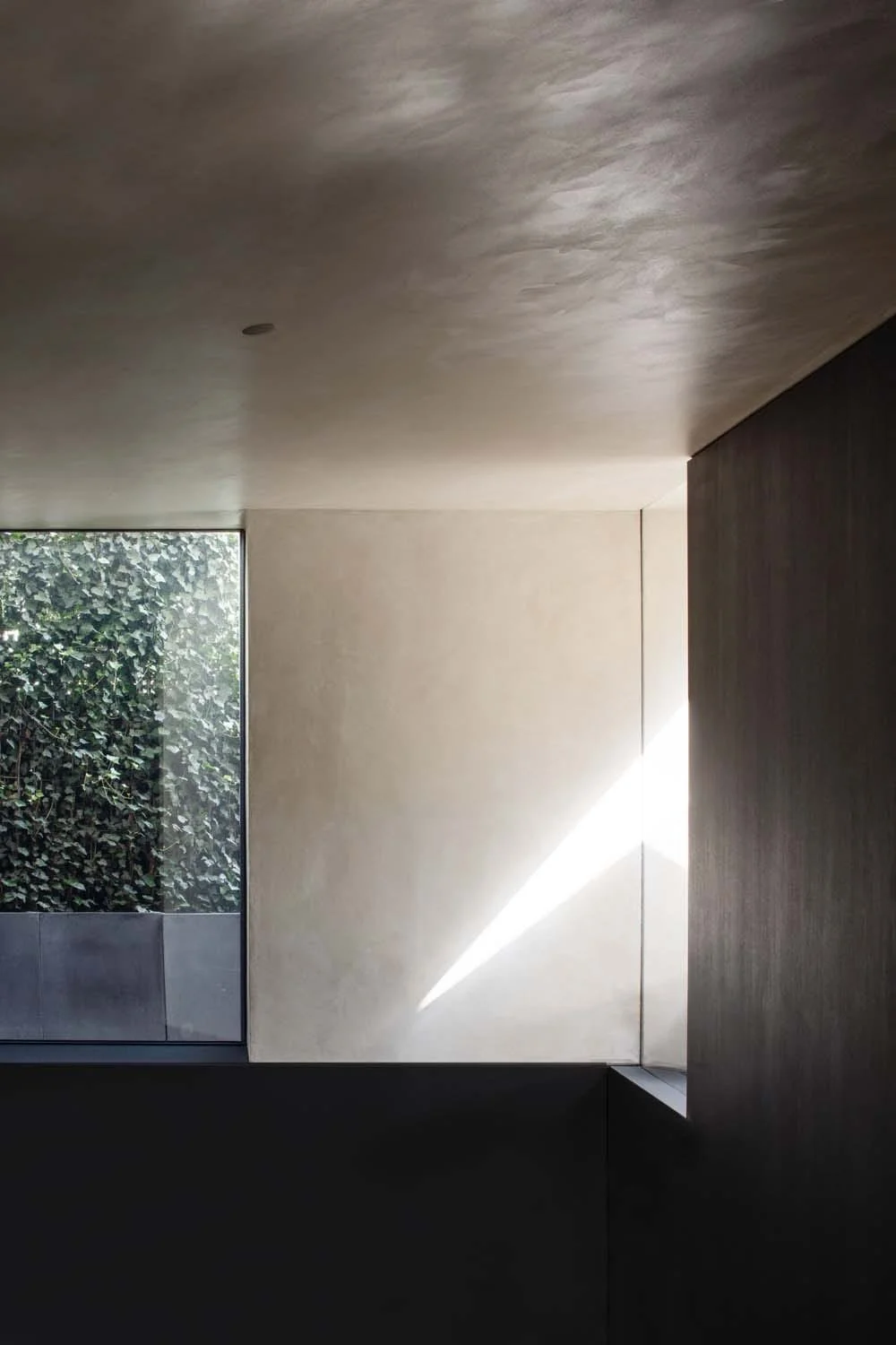 Natural light streams through geometric windows, enhancing the minimalist plaster walls and serene interior