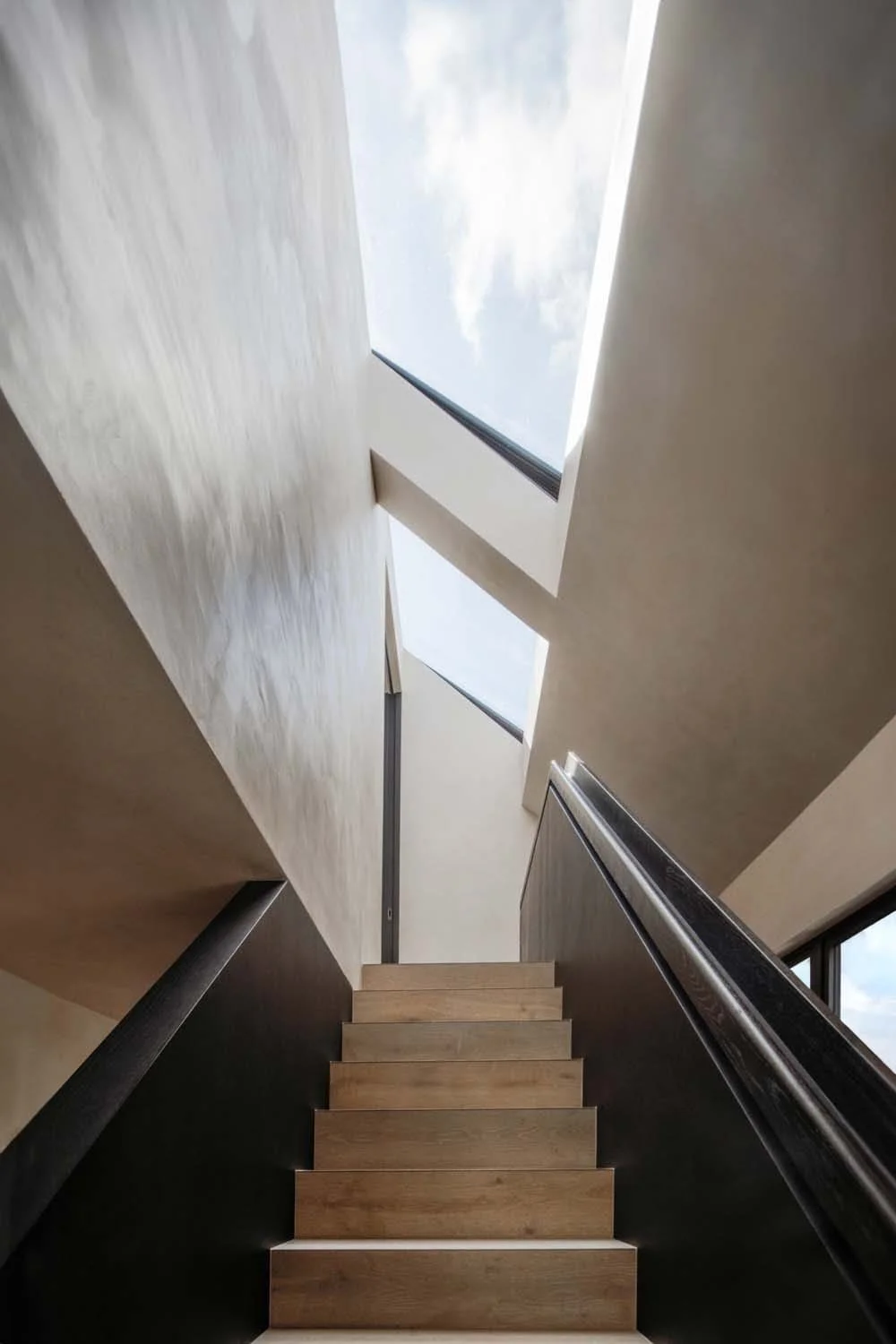 Staircase with skylight and clean lines. London architect’s elegant residential design combining light, space, and luxury