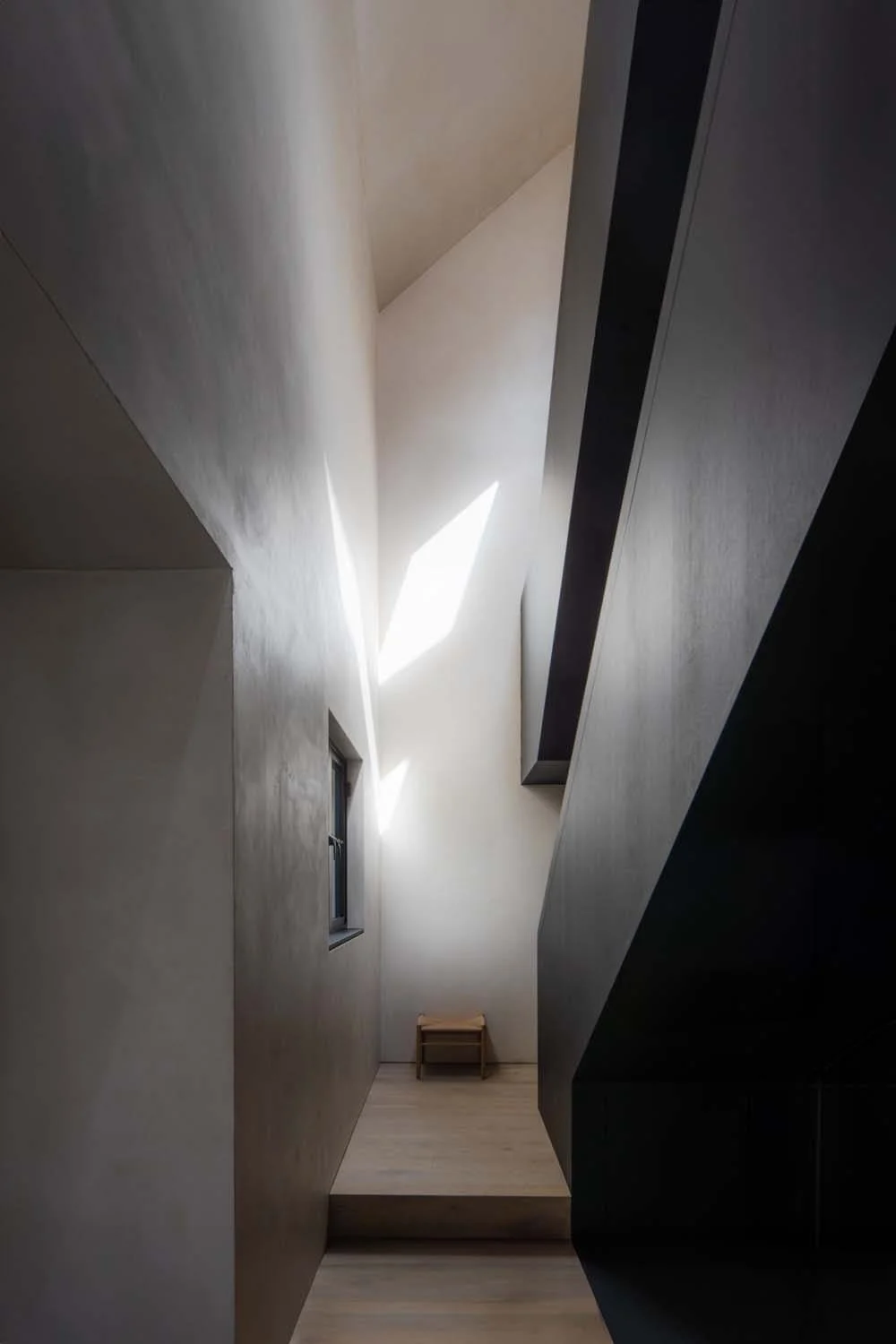 Minimalist hallway with sharp architectural lines, illuminated by natural light streaming through strategically placed windows