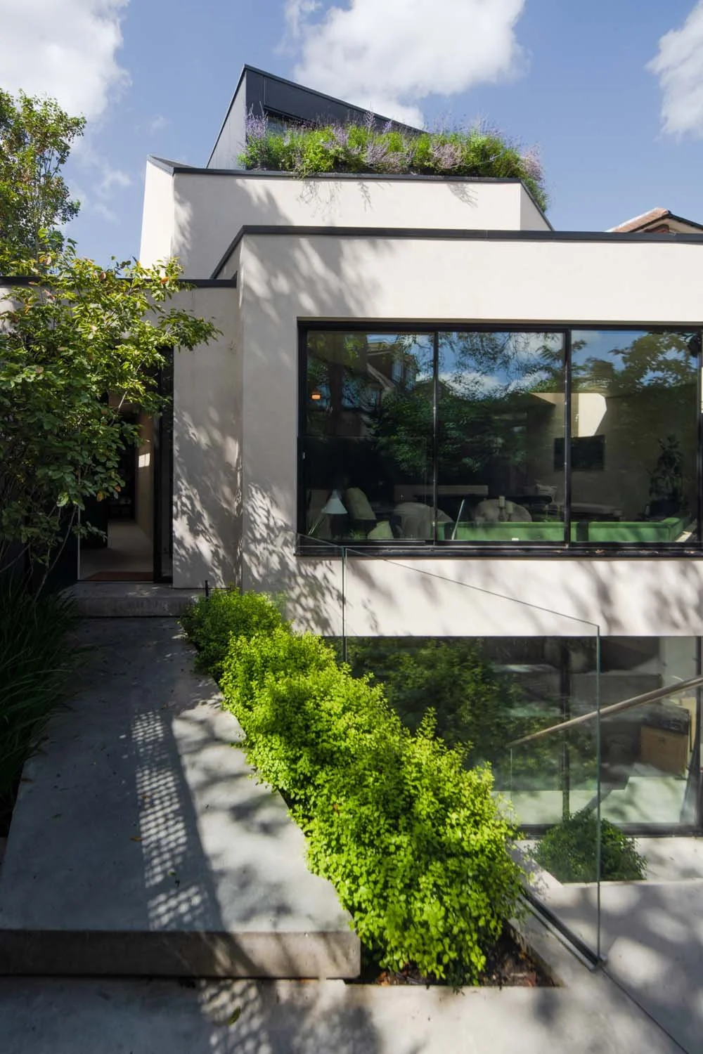 Rear exterior of Meadow Grove, featuring expansive windows and lush green landscaping, blending luxury and nature