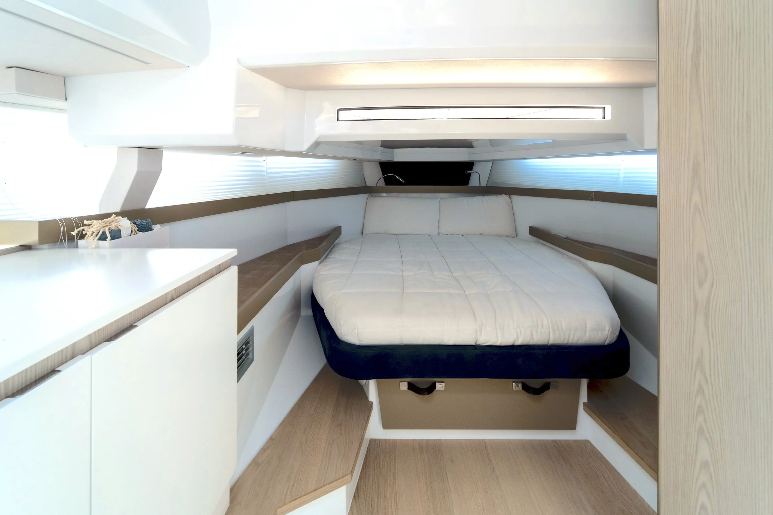 Interior of a modern boat or yacht bedroom with a bed, wooden accents, and minimalistic design.