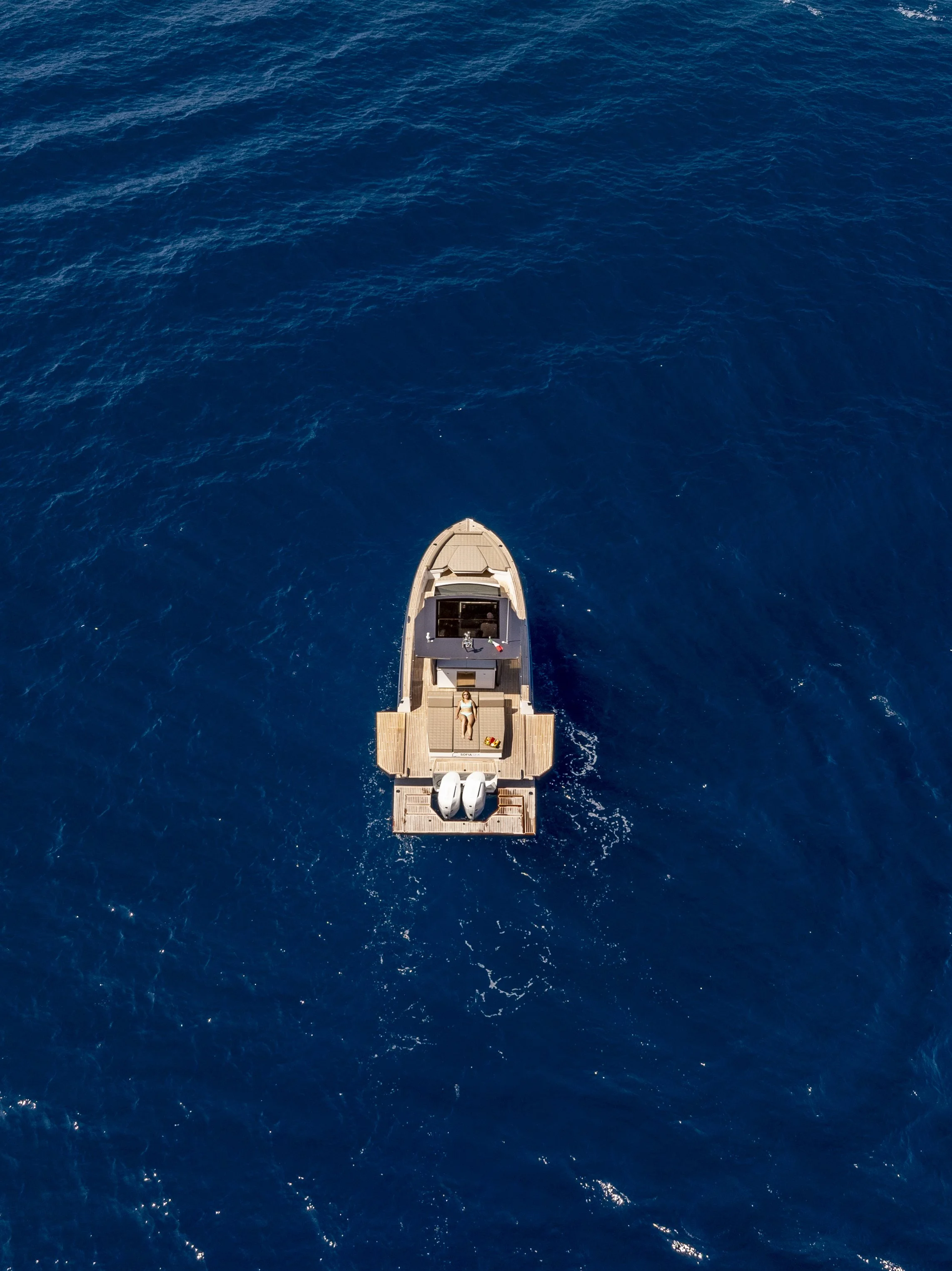 A boat with two outboard motors floating on the open ocean, viewed from above.