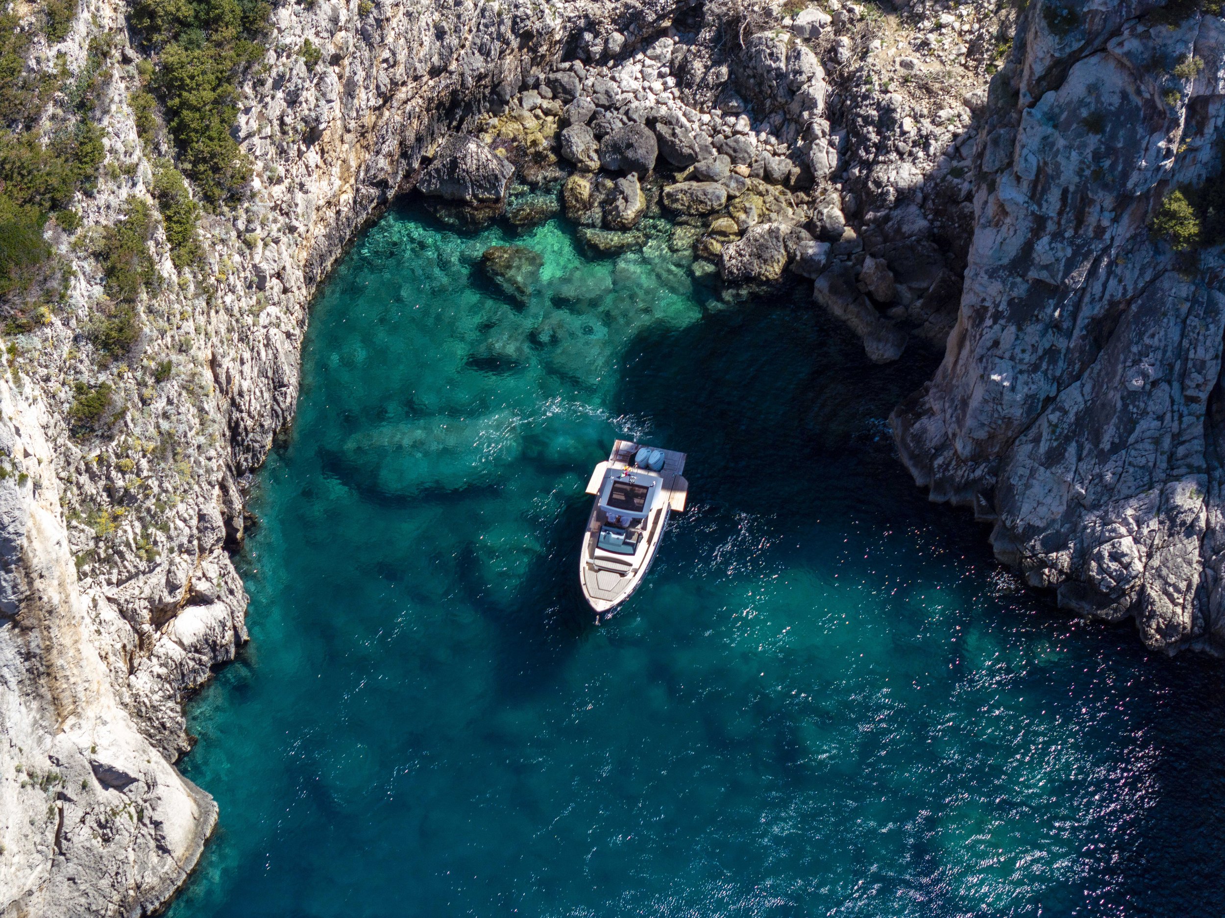 Aerial view of the Sofia Sea motorboat navigating the Mediterranean Sea near Capri, surrounded by dramatic cliffs and clear blue waters