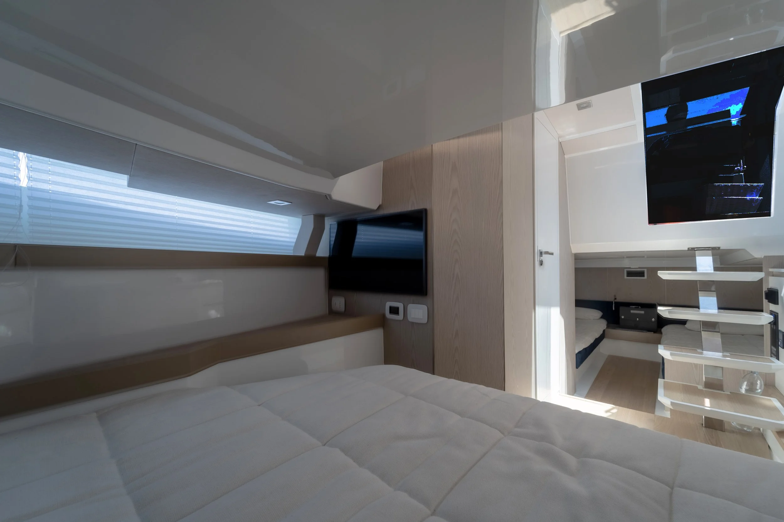 Interior of a modern hotel room with a bed, flat-screen TV, and natural light coming through a large window with blinds.