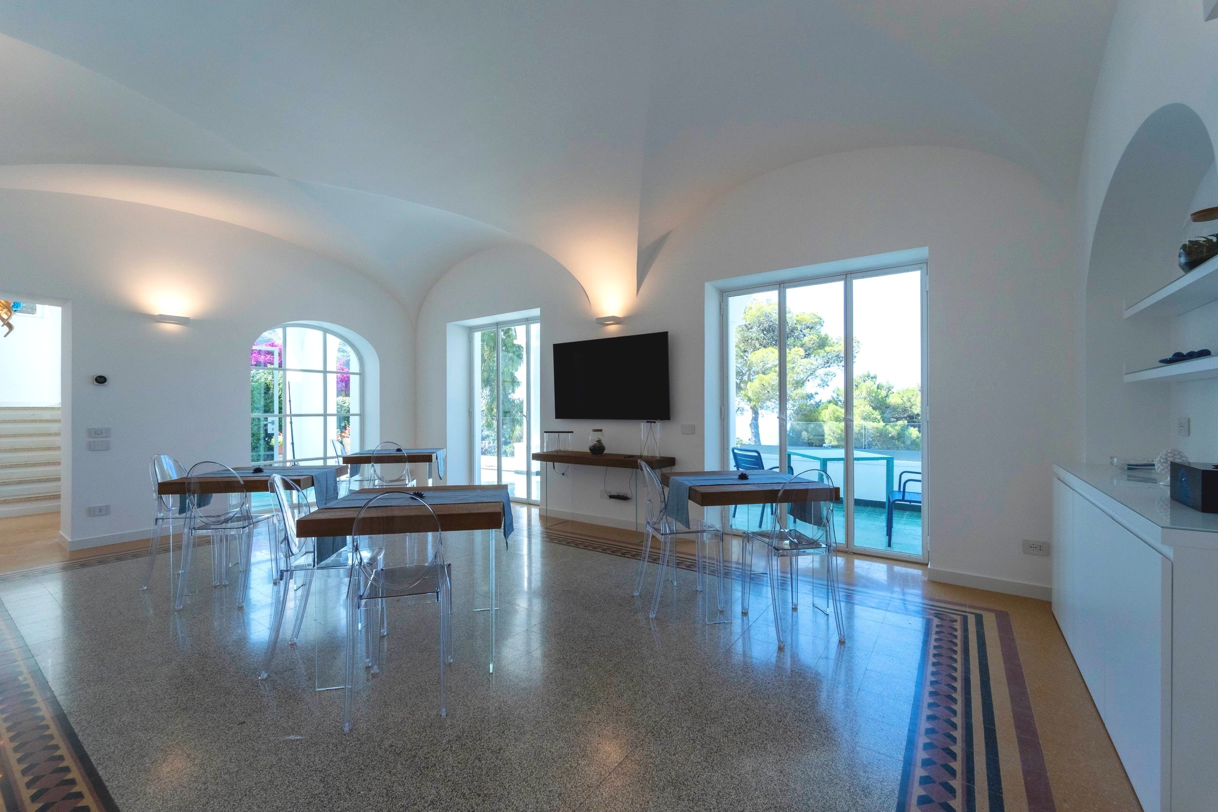 spacious open plan common room with tables chairs and a tv with beautiful views