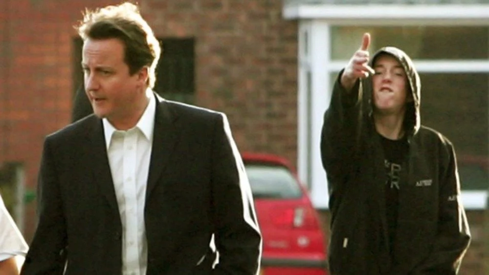David Cameron in Manchester in 2007 as Ryan Florence, 17, makes a gun gesture behind him.jpg