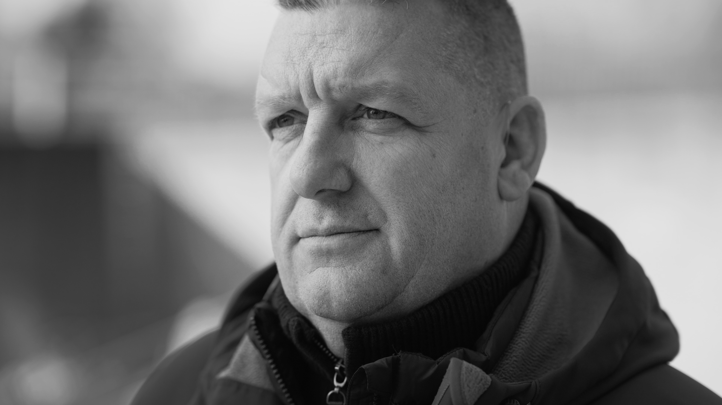Close-up black and white photograph of a middle-aged man with short hair, looking serious and contemplative.