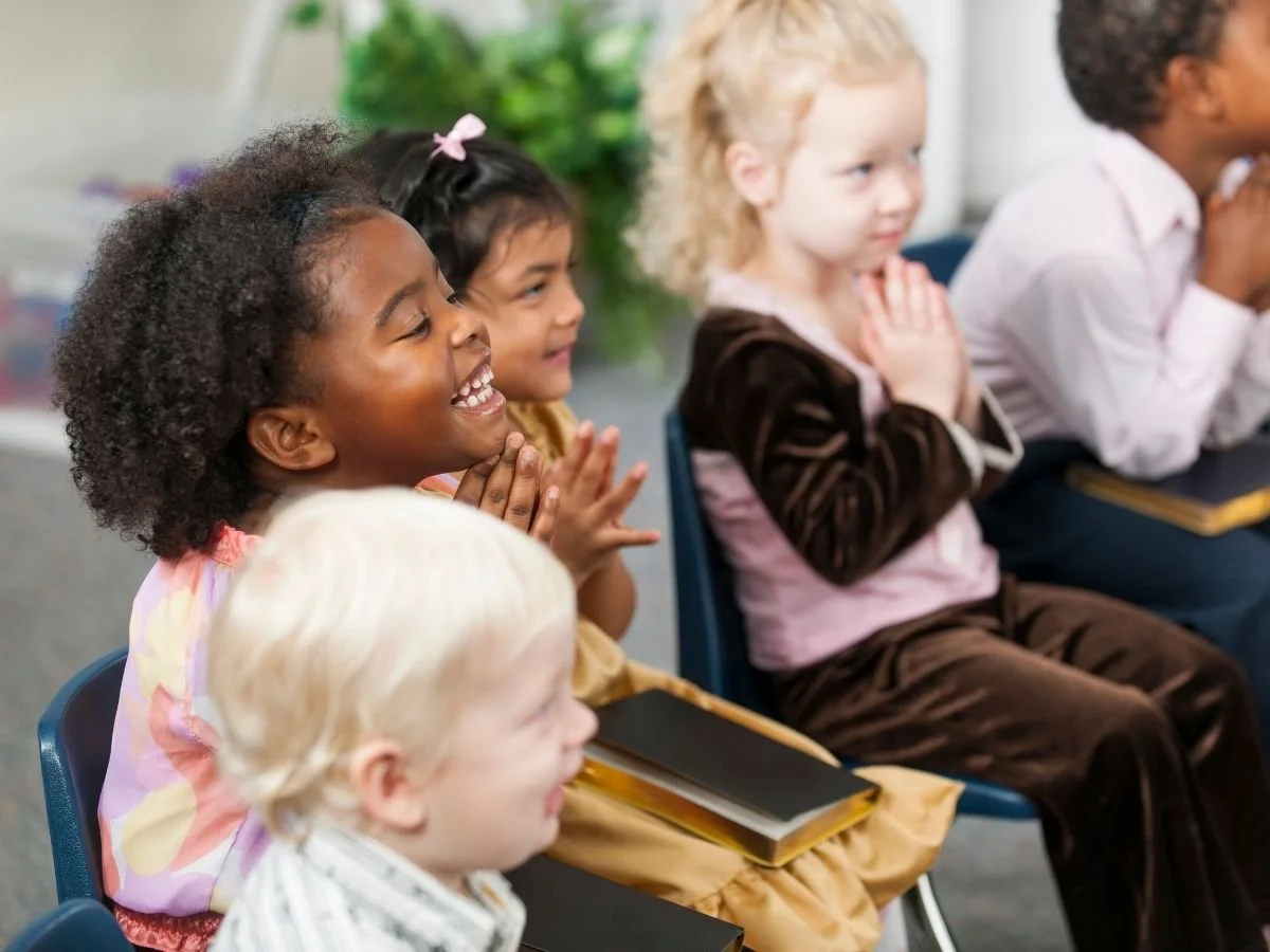 young children of various ethnicities are praying together happily at a microschool in Nashville.