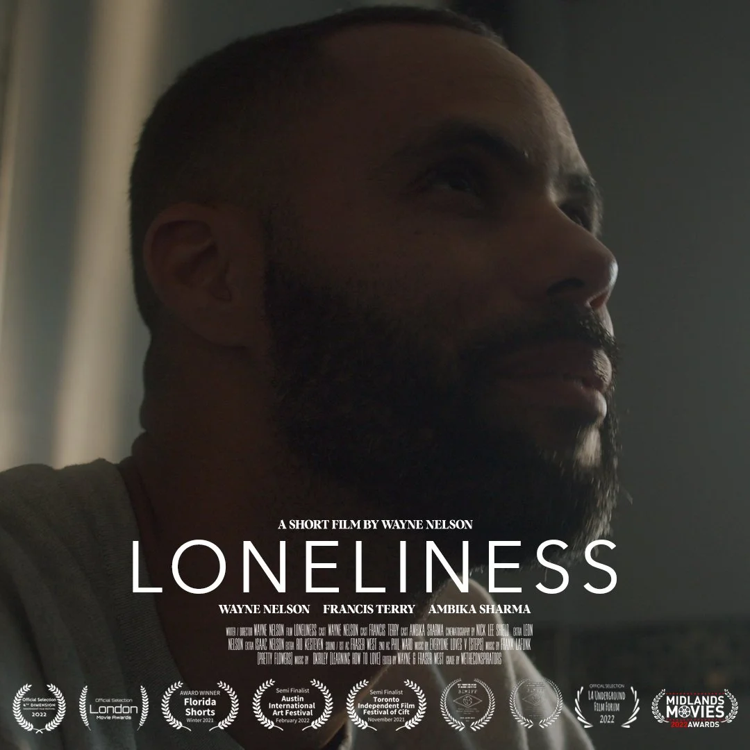 Close-up of a man with a beard looking to the side, with text overlay about the short film 'Loneliness' directed by Wayne Nelson.